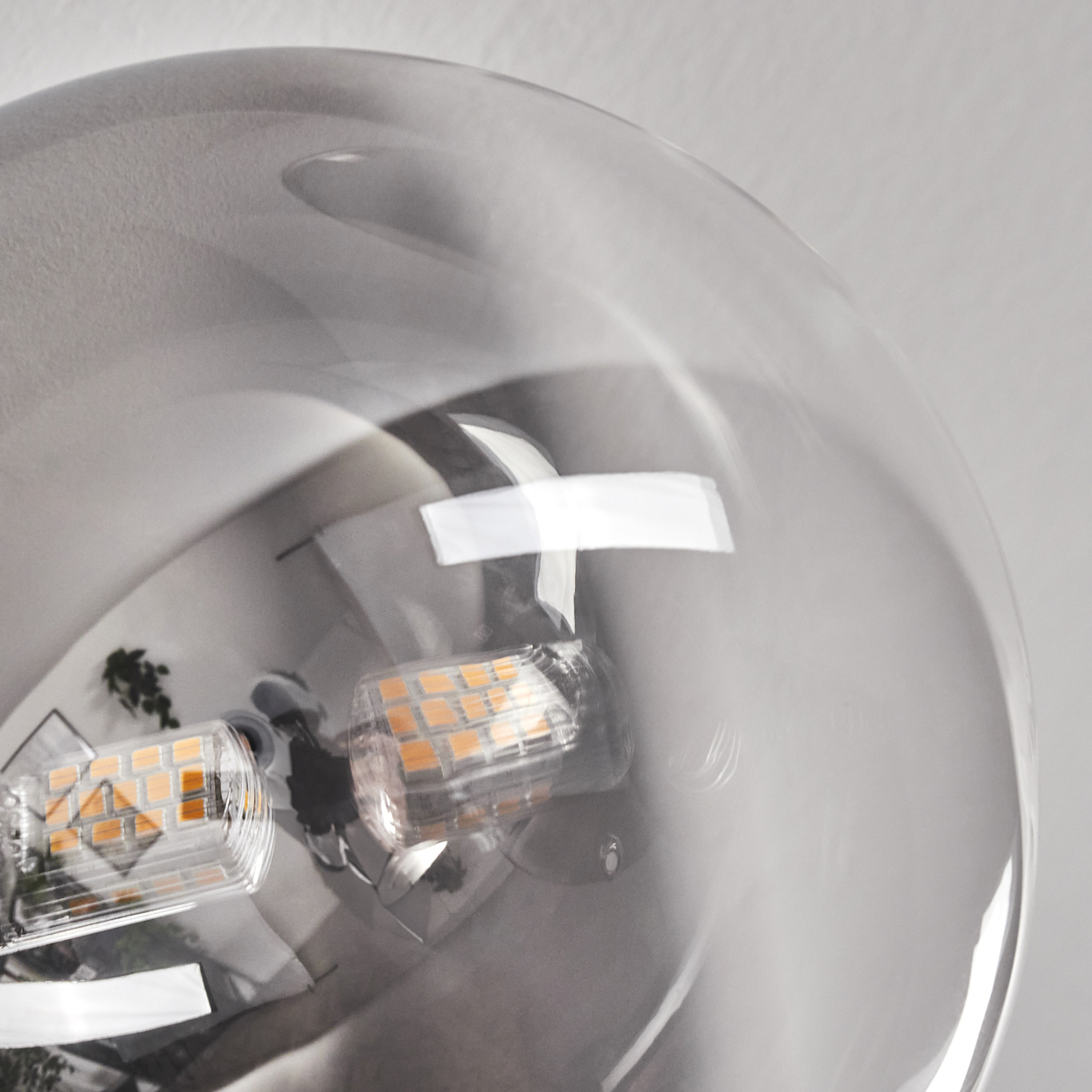 Nahaufnahme einer durchsichtigen Glühbirne mit zwei kleinen LED-Leuchtelementen. Der Hintergrund ist eine weiße Wand.