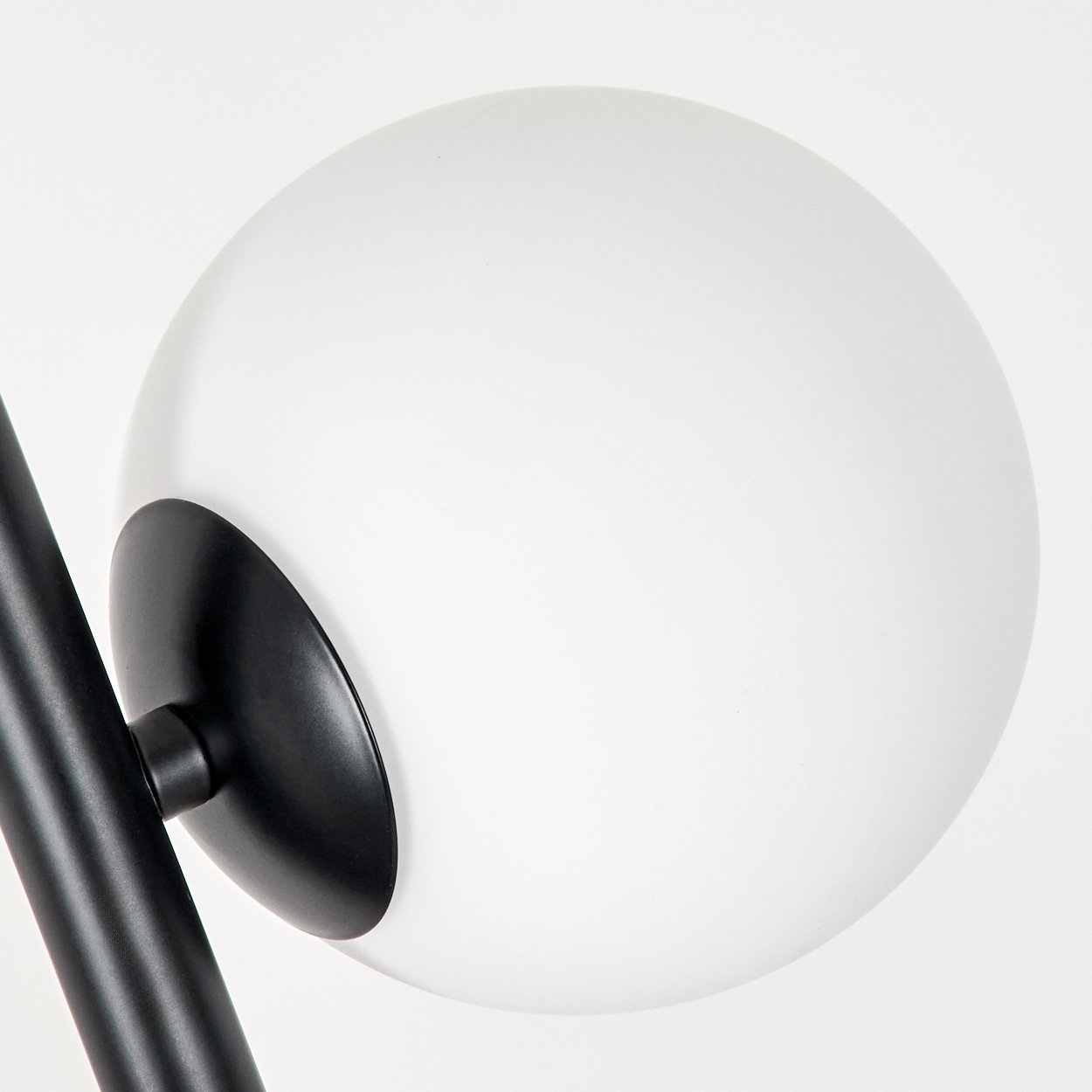 Eine moderne Lampe mit großem, weißem, kugelförmigem Schirm. Der Schirm ist an einem schwarzen Arm und Sockel befestigt.