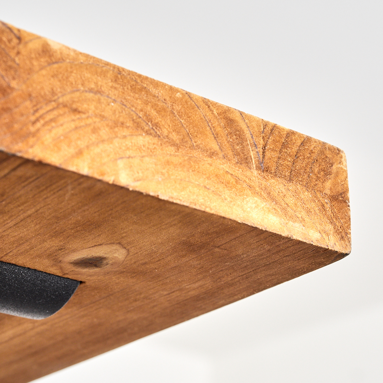 Nahaufnahme eines Holzregals mit sichtbarer Maserung. Unten ist eine schwarze Metallstütze befestigt. Weißer Hintergrund.