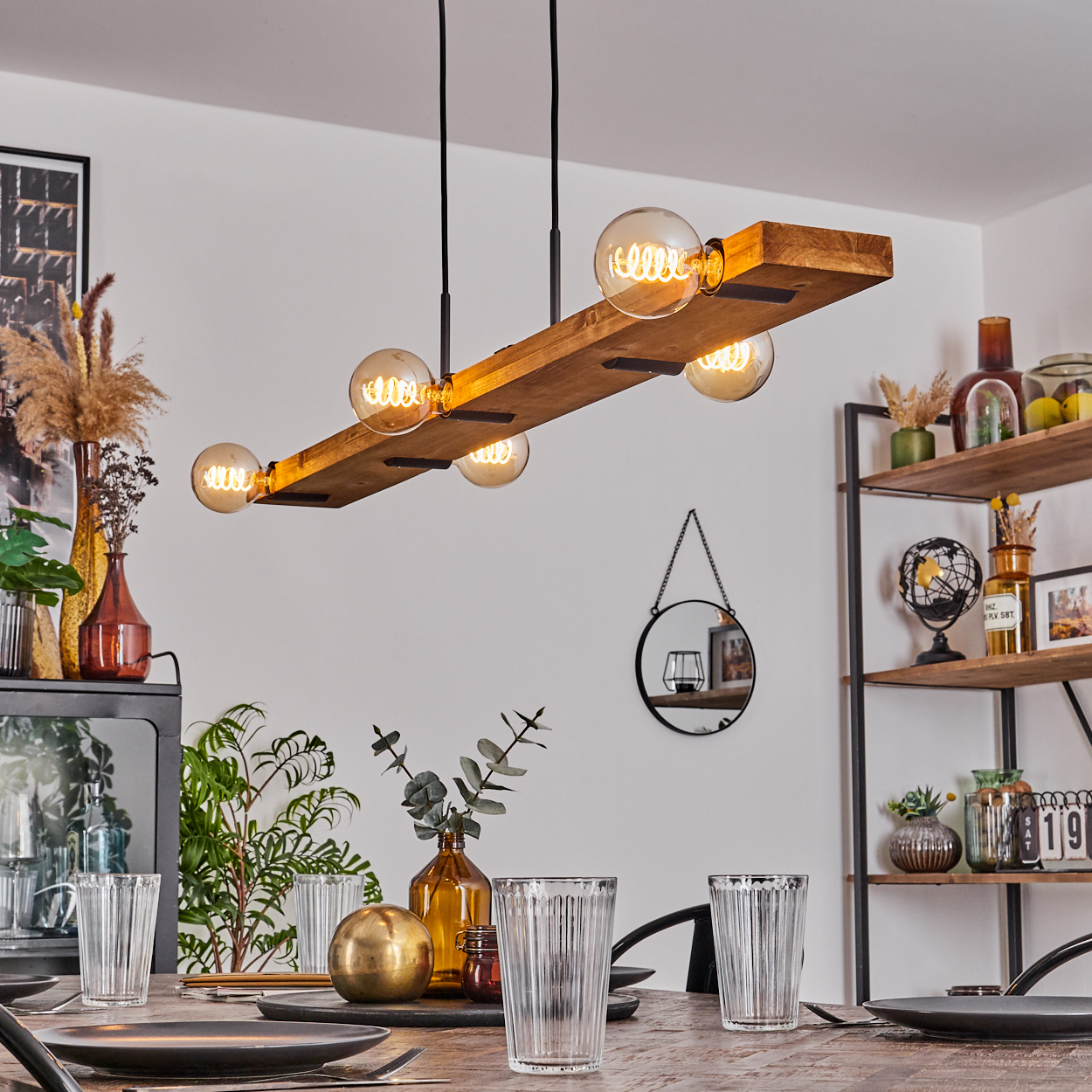 Ein Esszimmer mit einer Holzbalken-Beleuchtung, Tischgedeck und Dekorationsgegenständen auf Regalen und einem Schrank.