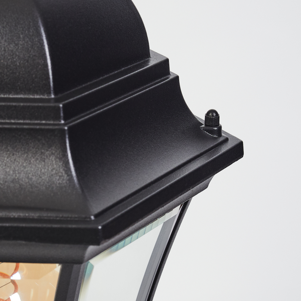 Nahaufnahme einer schwarzen Außenlampe. Der Lampenkopf ist detailliert, mit einer kleinen Schraube. Glasplatten sind unten sichtbar.