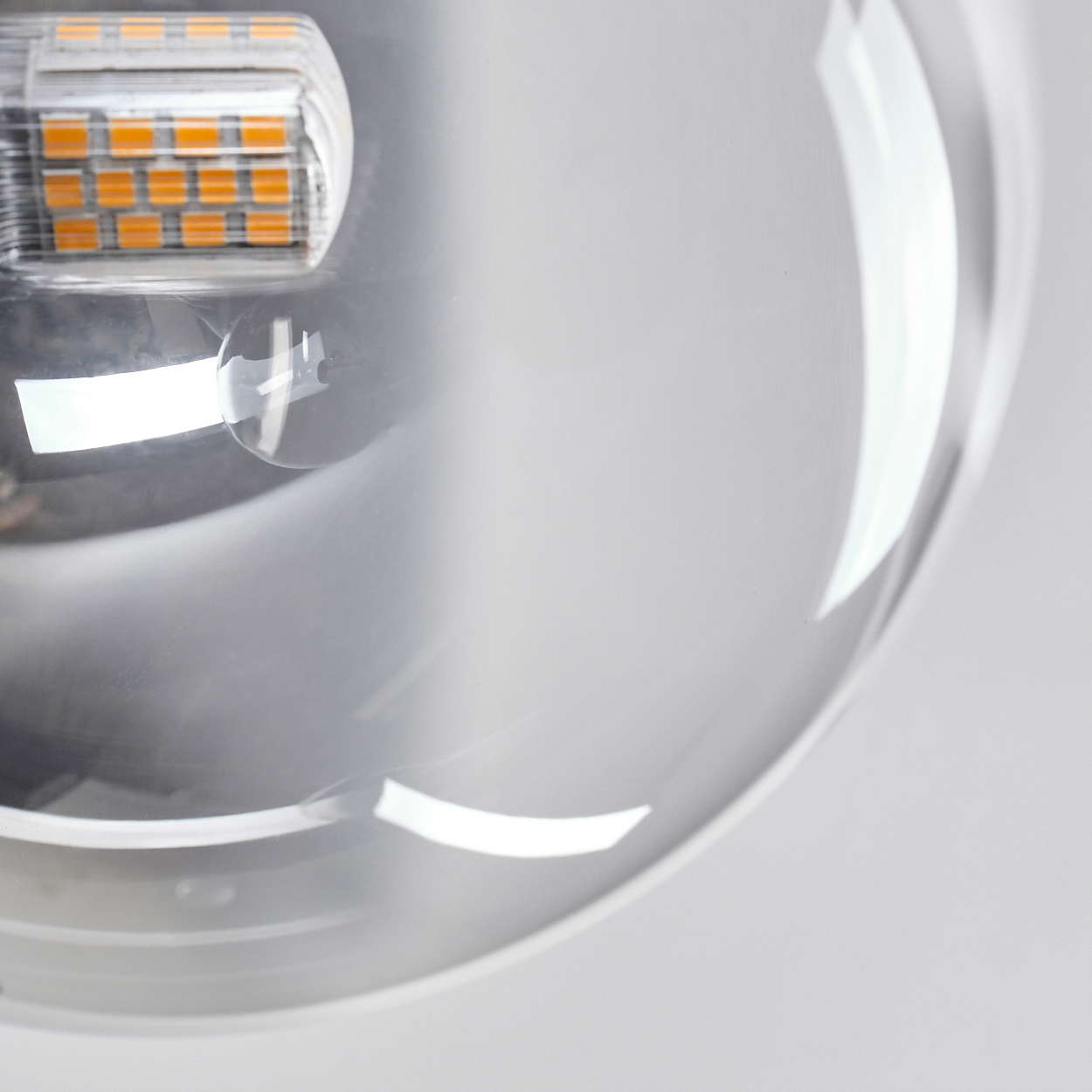 Nahaufnahme einer modernen Leuchte. Sie hat ein klares, kugelförmiges Glasgehäuse mit einem Abschnitt orangefarbener LED-Leuchten.