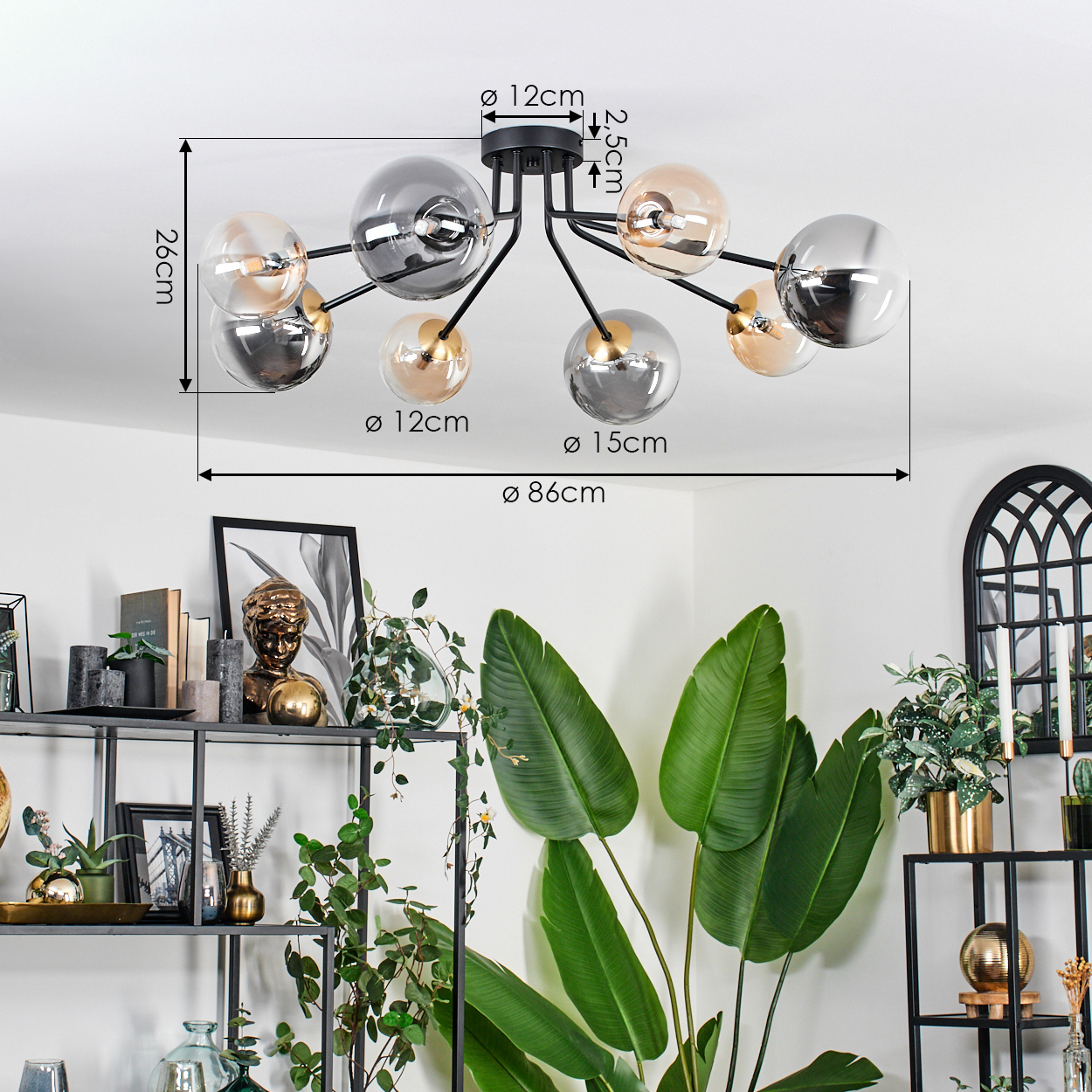 Eine moderne Deckenleuchte mit Glaskugeln hängt von der Decke. Darunter Regale mit Dekorationen und Pflanzen sowie große grüne Blätter.