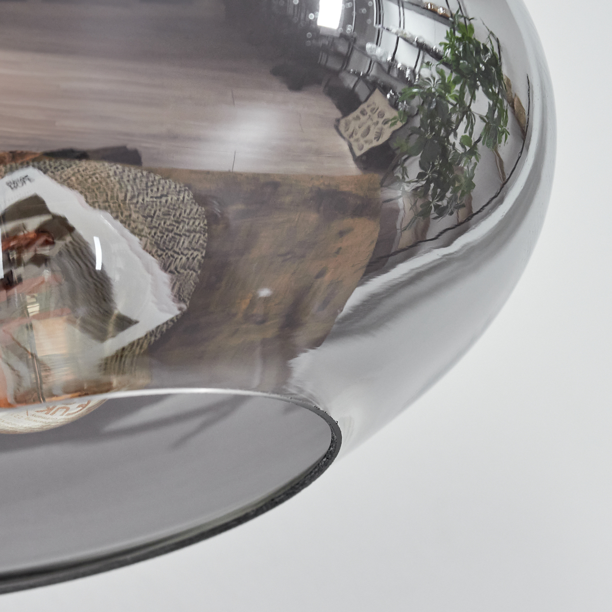 Eine reflektierende Glaskugel mit der Reflexion eines Raumes. Ein Tisch, eine Pflanze und andere Objekte sind sichtbar.
