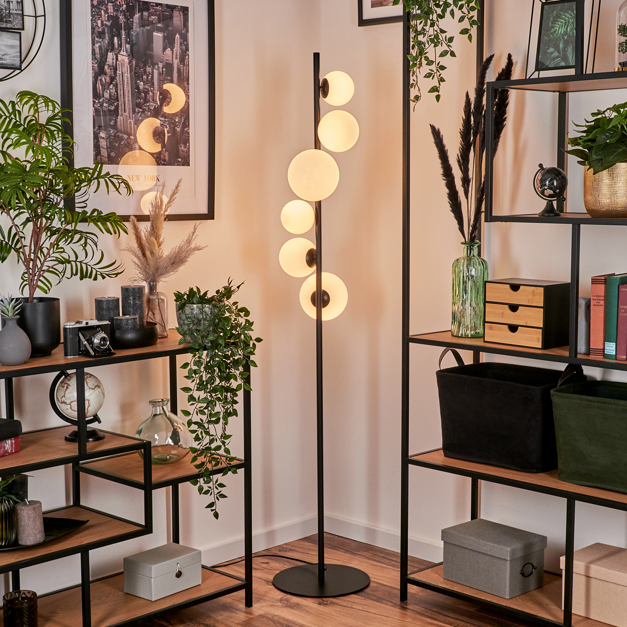 Eine moderne Ecke des Wohnzimmers mit Stehlampe, Regalen mit Pflanzen und einem New York City-Poster.