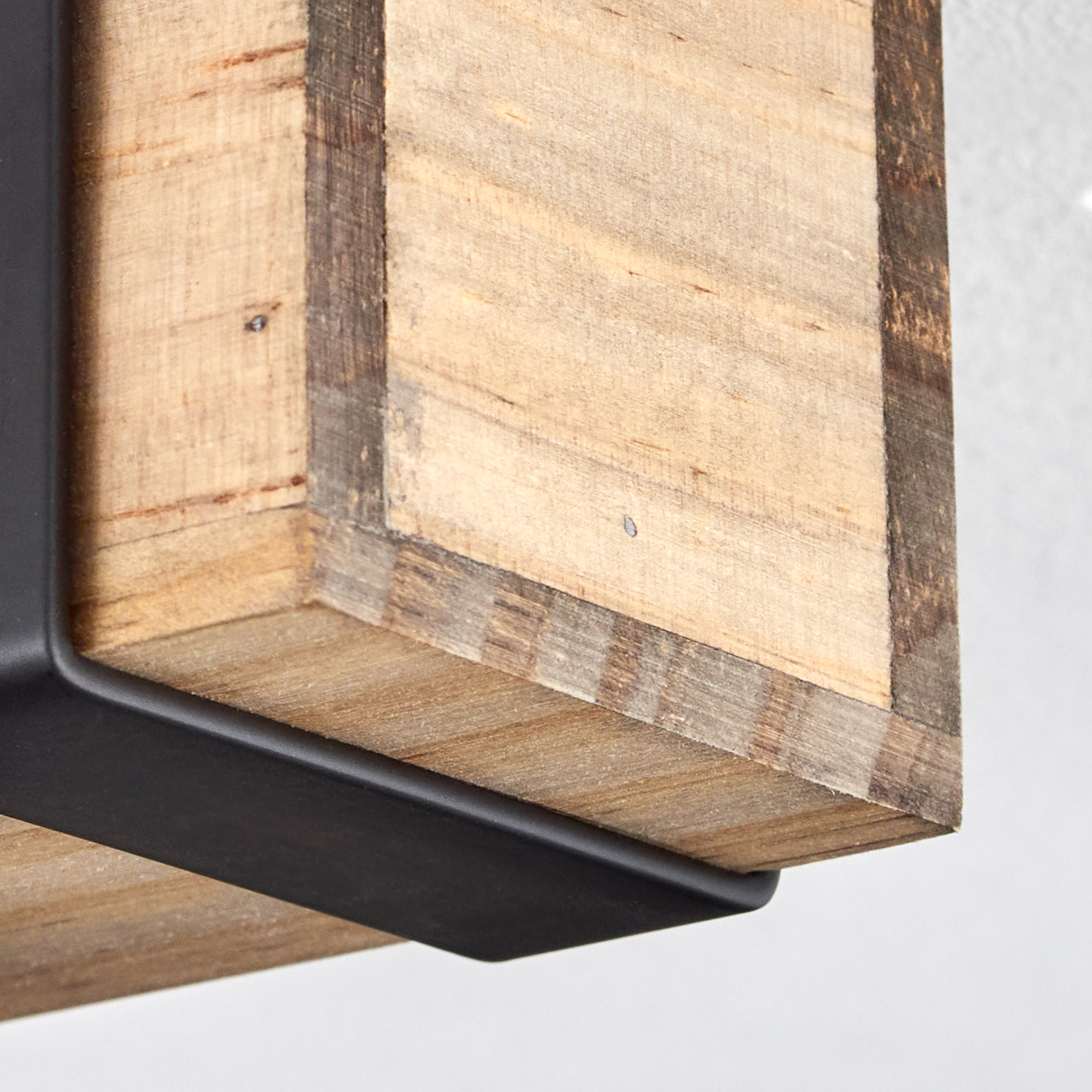 Nahaufnahme eines Holzblocks mit Metallhalterungen. Das Holz ist hellbraun mit sichtbarer Maserung. Metall ist schwarz und bildet eine Stütze.