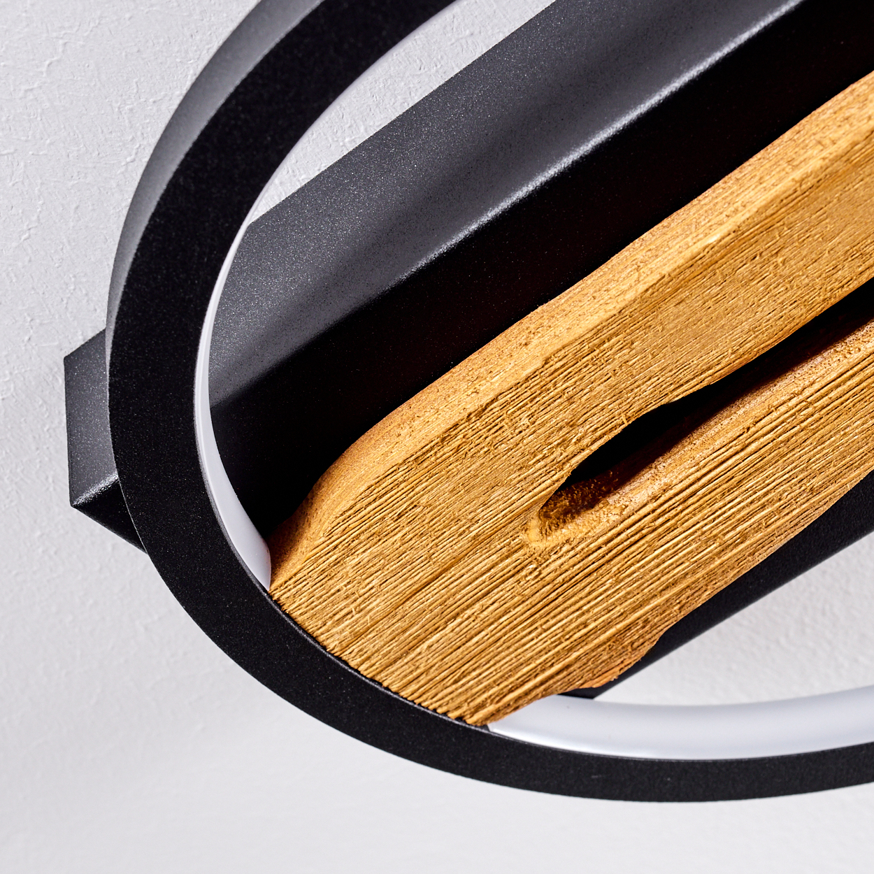 Nahaufnahme einer modernen Leuchte mit Holzelement. Sie hat einen schwarzen Metallrahmen und ein weißes Innenlicht. Der Hintergrund ist weiß.