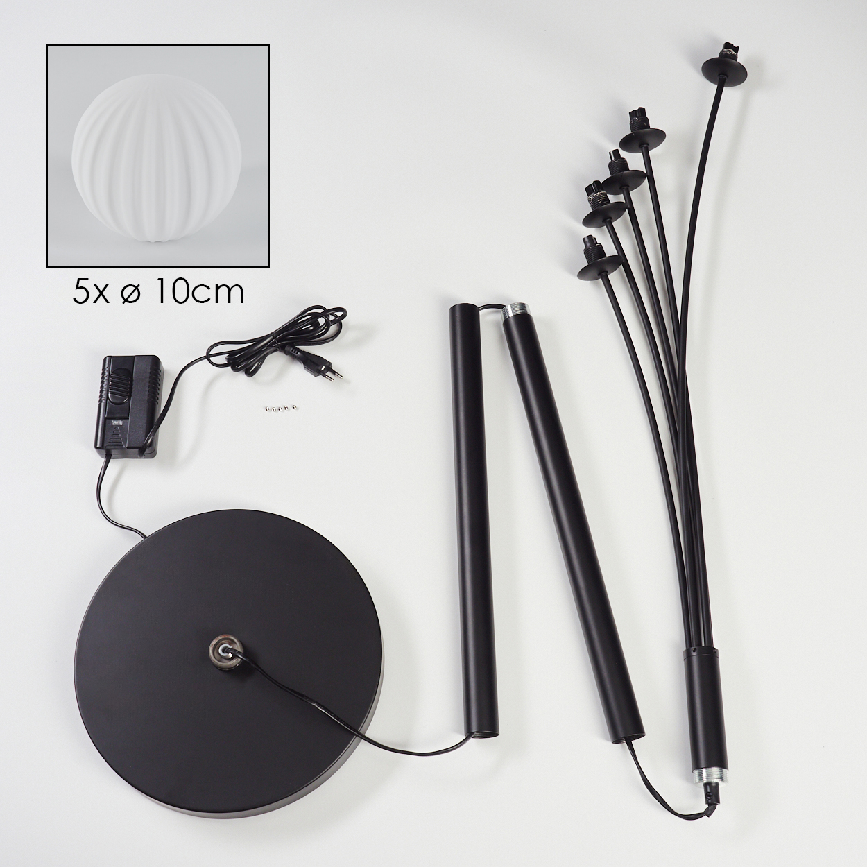 Zerlegte Teile einer schwarzen Stehlampe: Sockel, Stangen, Drähte und Lampenköpfe. Eine weiße Glühbirne wird in einer Box gezeigt. Weißer Hintergrund.