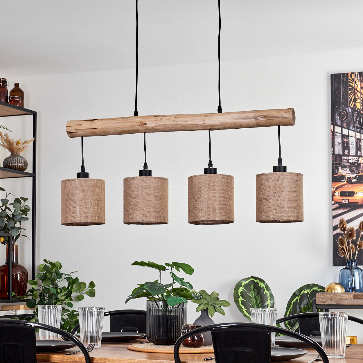 Ein Holzbalken mit vier Pendelleuchten. Ein Esstisch mit Pflanzen und Gläsern. Ein Gemälde mit gelben Taxis.