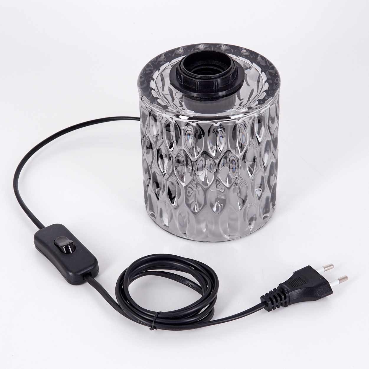 Eine graue Glaslampe mit schwarzem Kabel, Schalter und Stecker auf weißem Grund. Die Lampe hat eine strukturierte Oberfläche.