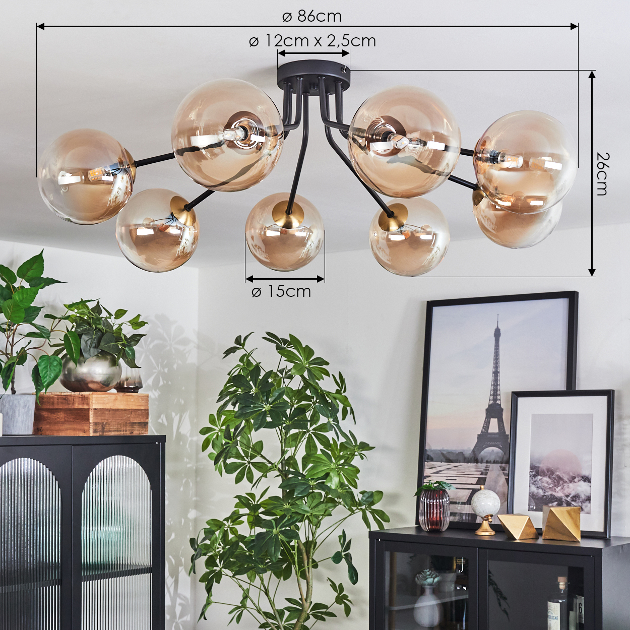 Deckenlampe mit acht bernsteinfarbenen Glaskugeln. Darunter ein schwarzer Schrank mit Pflanzen, gerahmter Kunst und Dekorationsartikeln.