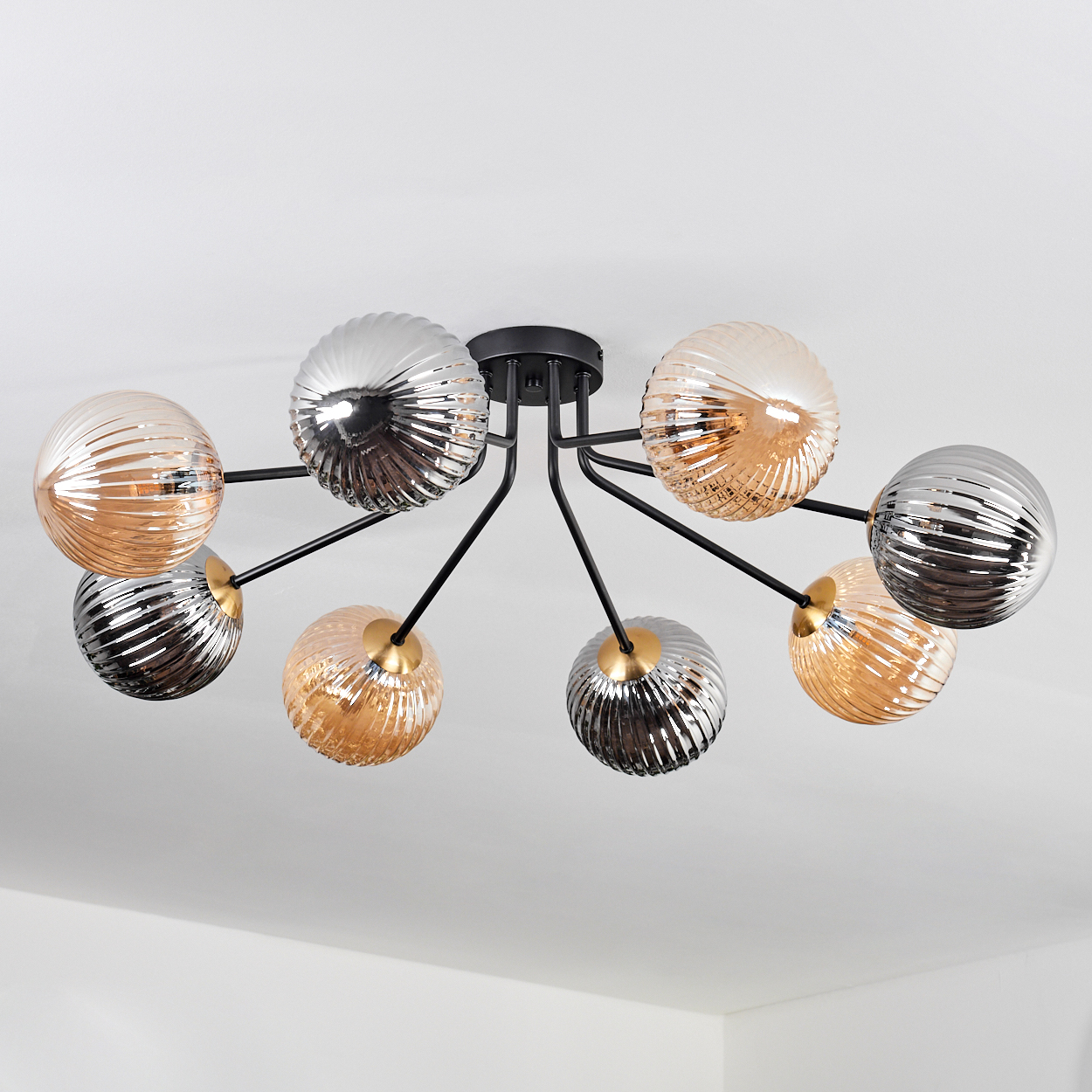 Deckenleuchte mit acht Glasschirmen in Silber und Bernstein, an schwarzen Metallarmen an einer weißen Decke befestigt.