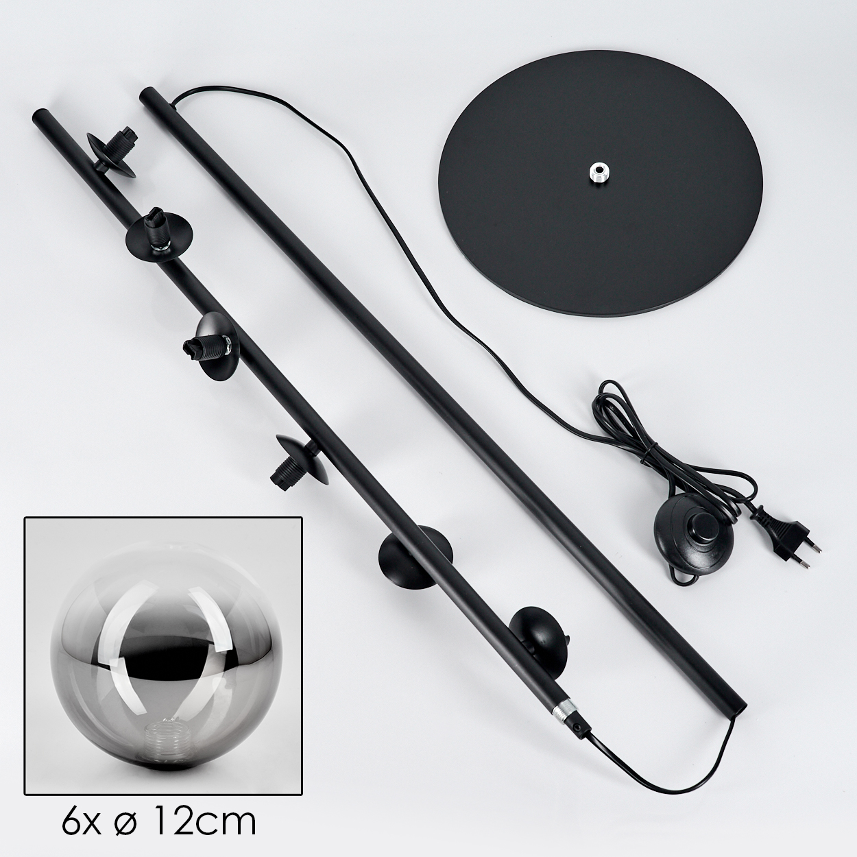 Zerlegte schwarze Stehlampe mit Sockel, Stangen und Glaskugel. Der Sockel ist rund. Teile liegen auf weißem Untergrund.