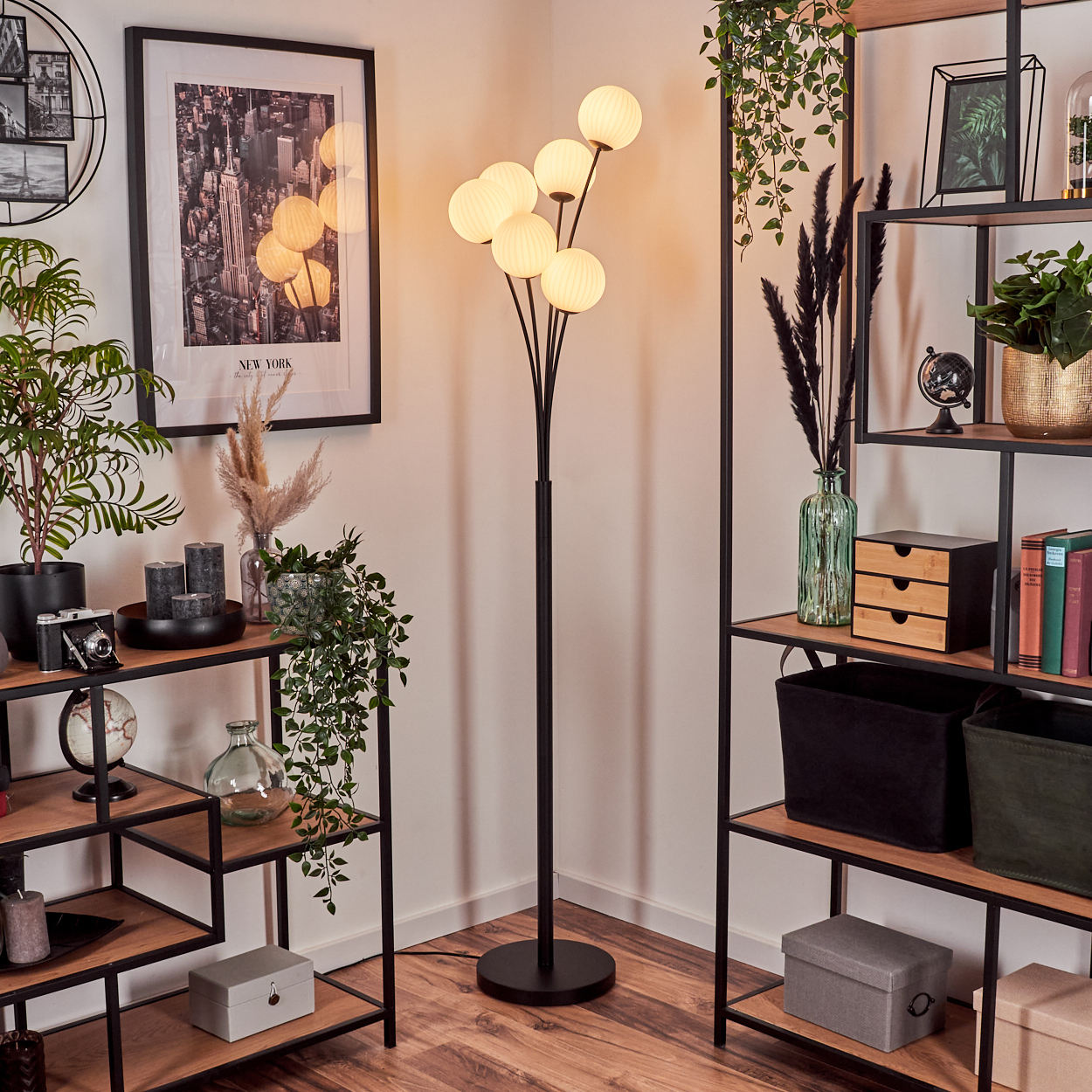 Ein Raum mit Stehlampe, Regalen und Dekorationsartikeln. Ein New York City-Druck hängt an der Wand.