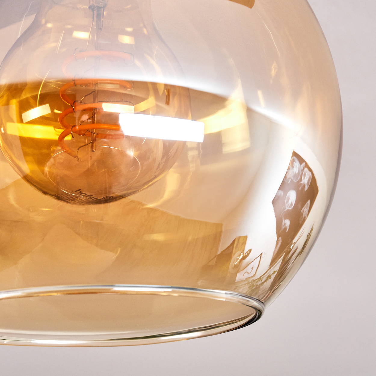Nahaufnahme einer Glasglühbirne. Die Glühbirne hat einen orangefarbenen Glühfaden und ist in transparentem, bernsteinfarbenem Glas eingeschlossen.