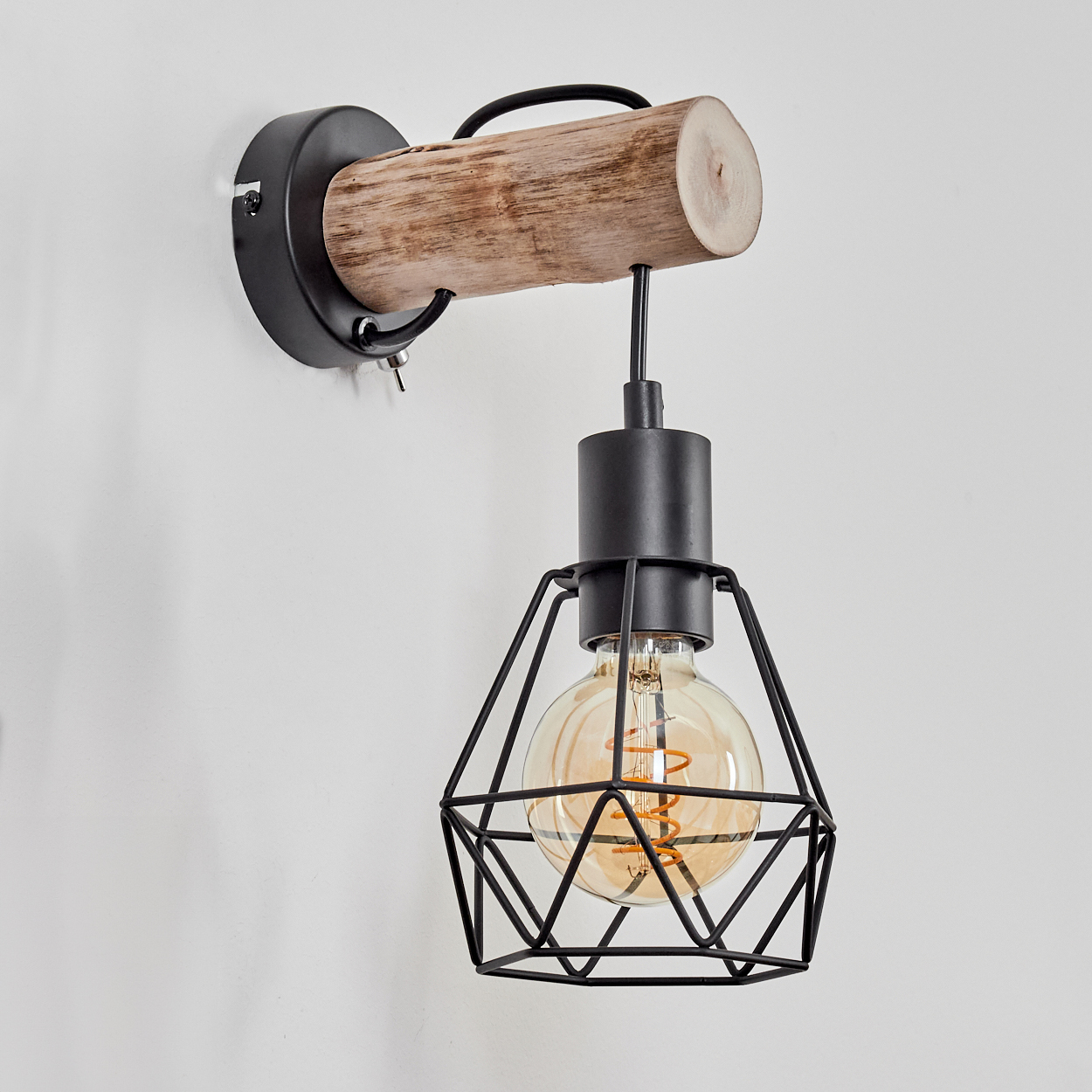 Eine Wandleuchte mit Holzbalken und schwarzem Metallkäfig um eine Glühbirne, vor einer weißen Wand.