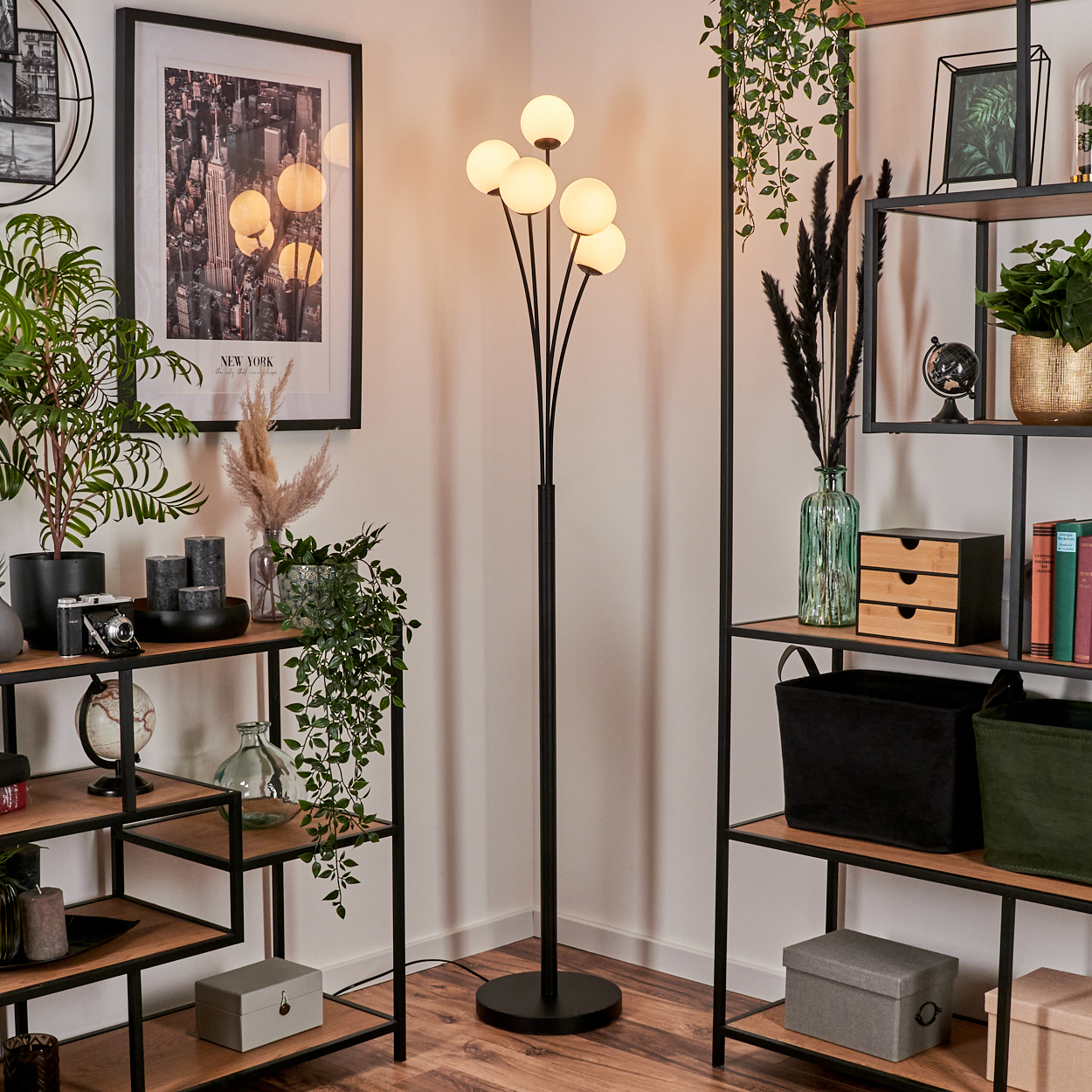 Eine Zimmerecke mit Stehlampe, Regalen, Pflanzen und einem New York-Bild. Regale sind mit Dekorationsartikeln gefüllt.