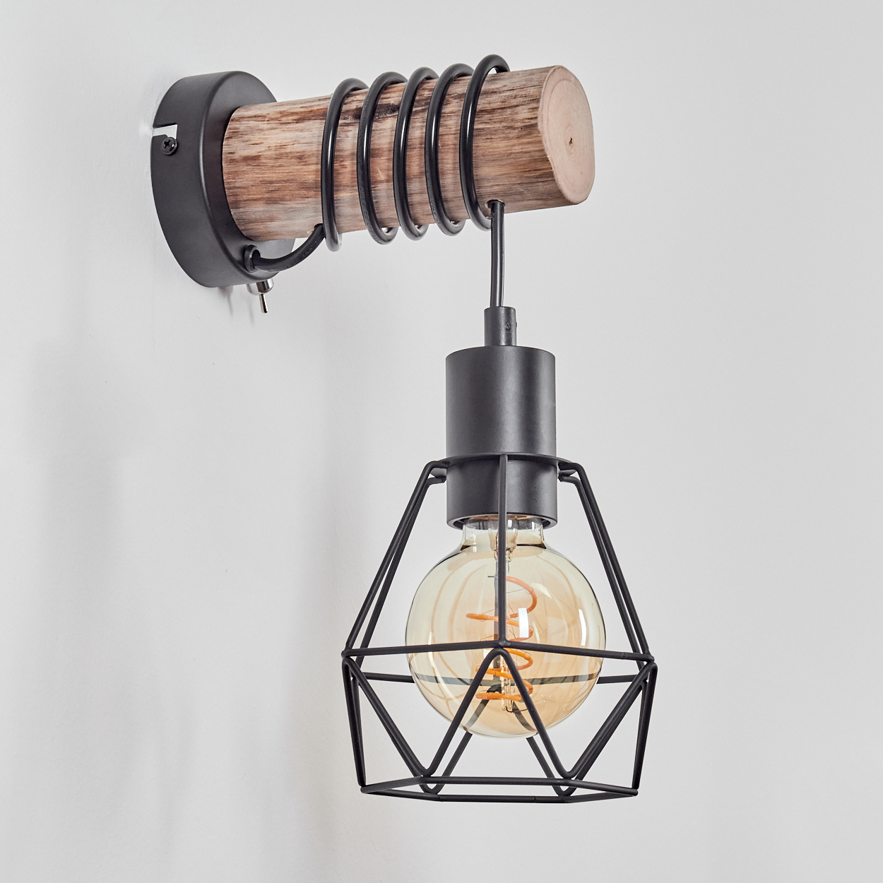 Eine Wandleuchte mit Holzbalken, schwarzem Metallkäfig und leuchtender Glühbirne. Der Hintergrund ist eine weiße Wand.