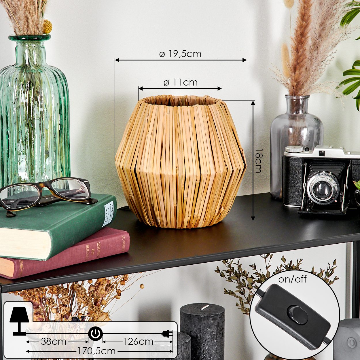 Eine Korblampe auf einem schwarzen Regal, mit einer Vase, Büchern, Brille und einer alten Kamera. Maße und Schalter sichtbar.