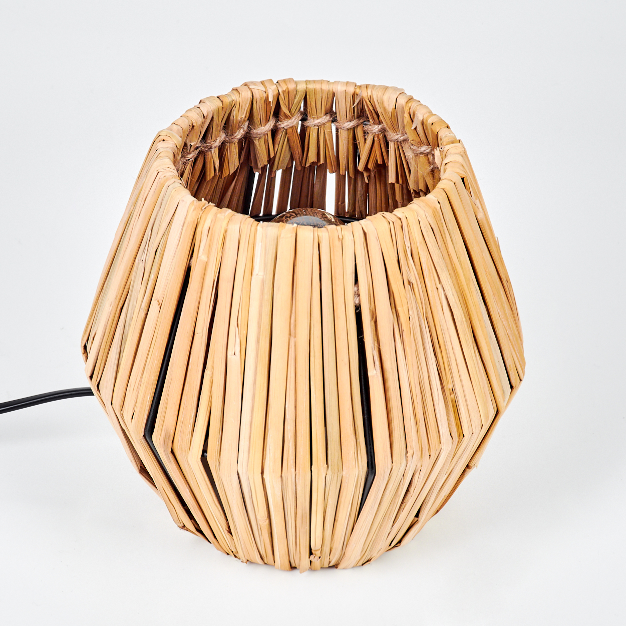 Eine dekorative gewebte Lampe mit schwarzem Netzkabel auf weißem Hintergrund. Die Lampe besteht aus hellbraunem, gewebtem Material.