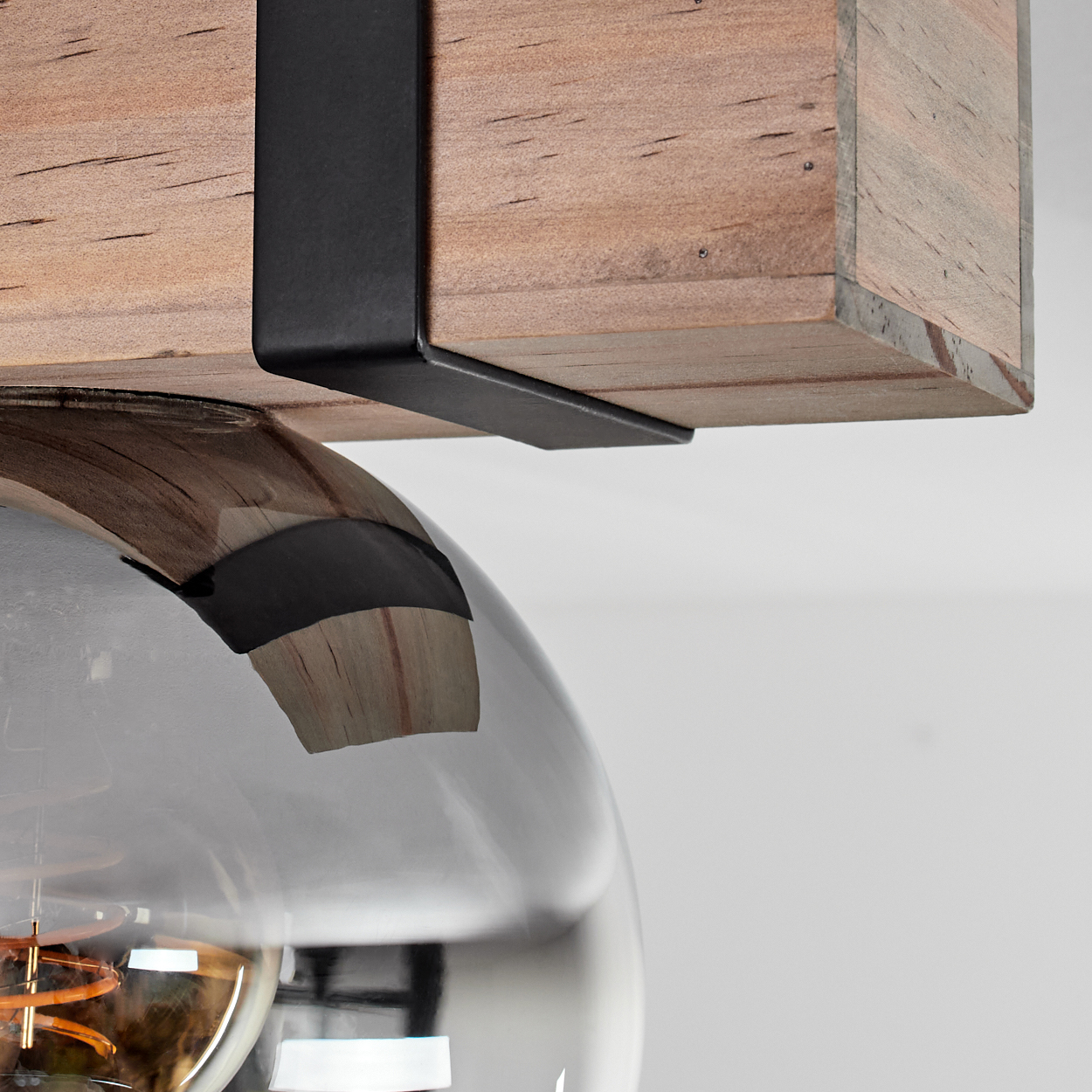 Nahaufnahme einer modernen Leuchte. Holzbalken mit schwarzer Metallstütze über einem großen, reflektierenden Glaskolben.