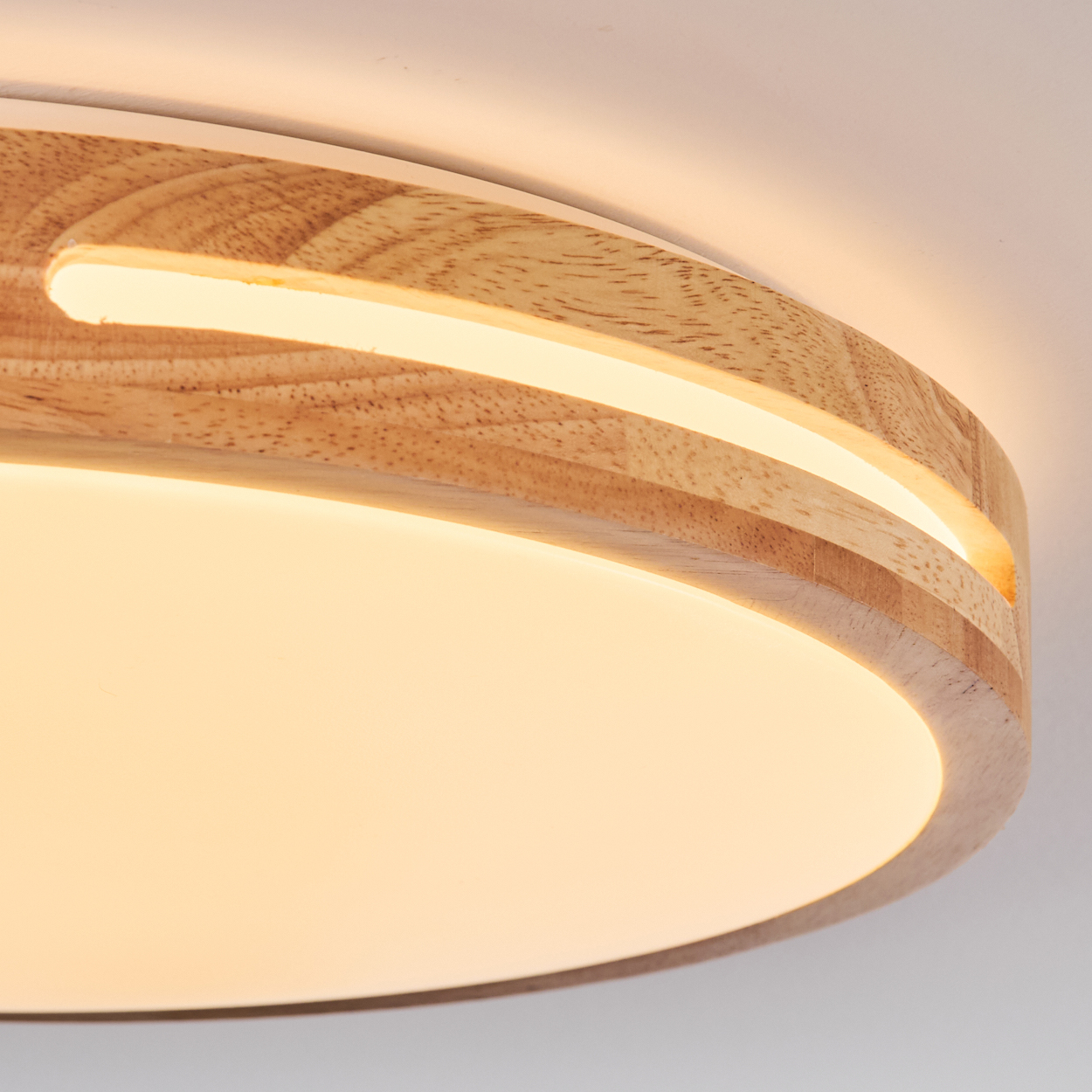Eine Deckenlampe aus Holz mit warmem Licht. Die Lampe hat einen kreisförmigen Holzrahmen mit leuchtendem Licht.