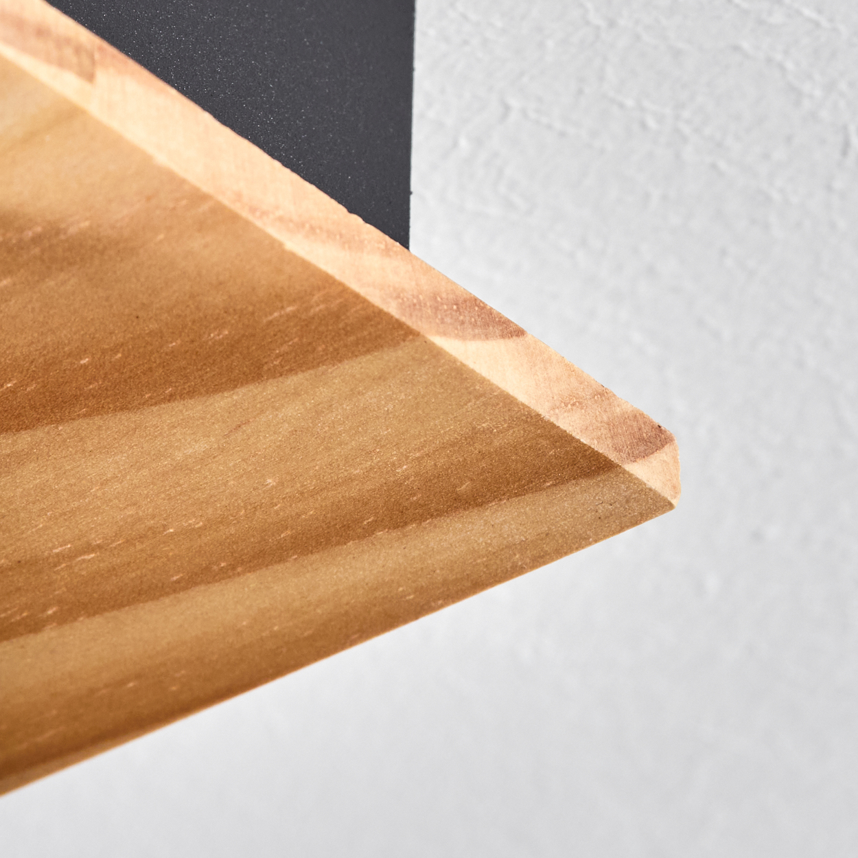 Nahaufnahme einer Holzeckablage mit schwarzer Halterung vor weißer Wand. Die Holzmaserung ist sichtbar.