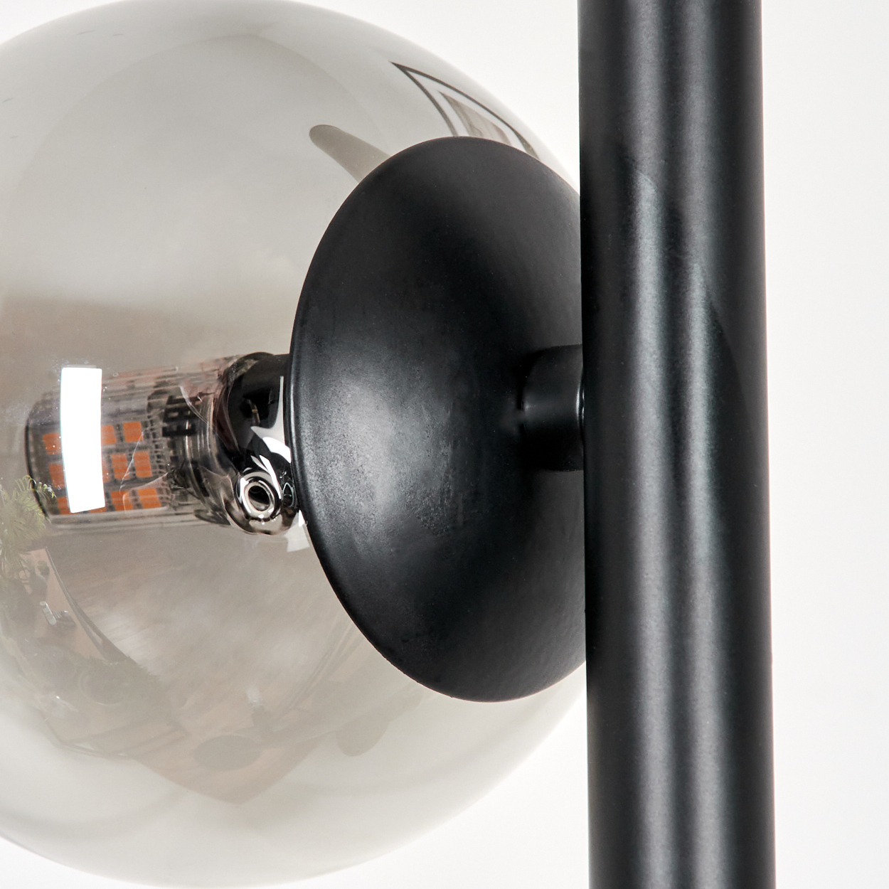 Nahaufnahme einer modernen Lampe. Sie hat eine runde Glaskugel, einen schwarzen kreisförmigen Schirm und eine schwarze vertikale Stütze.