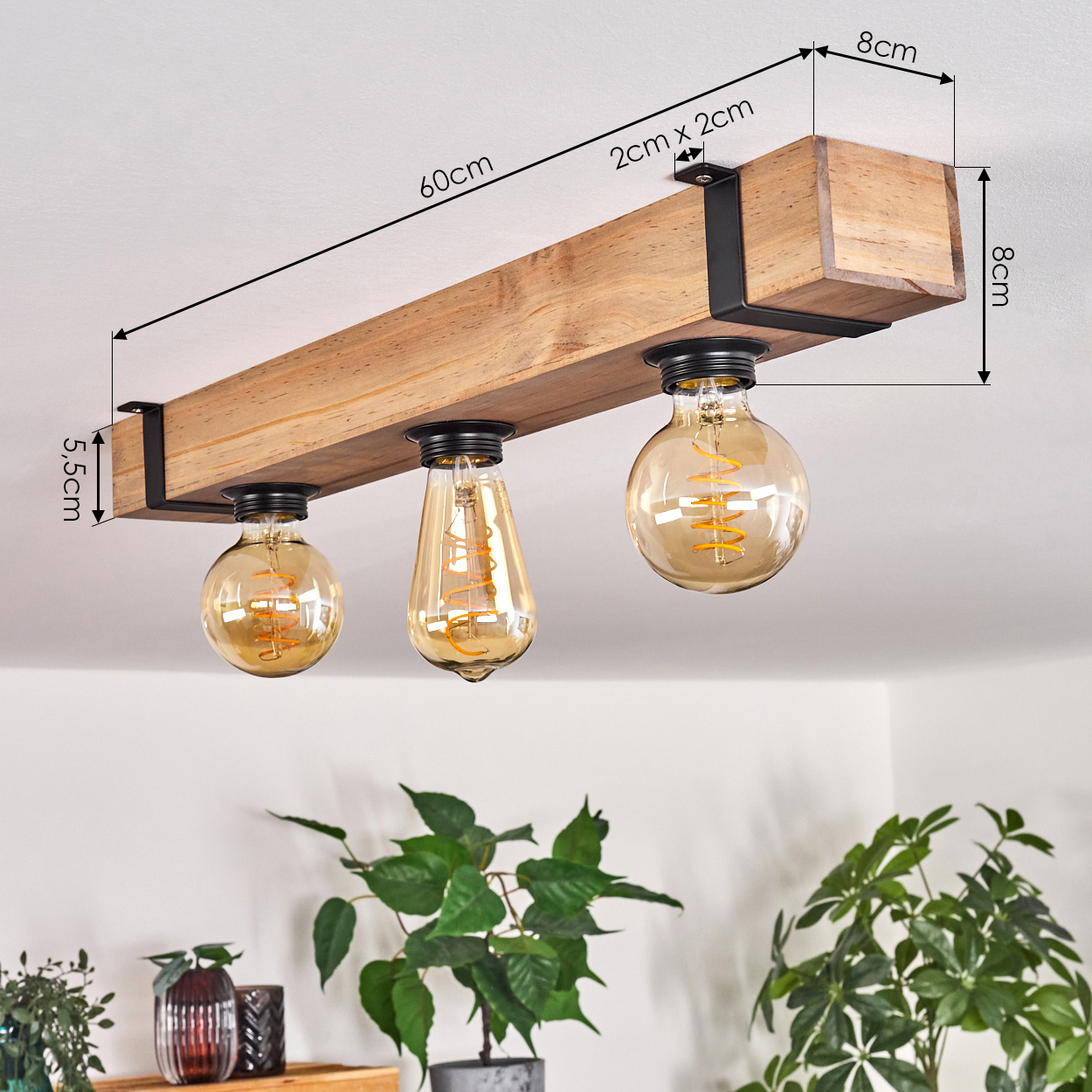 Holz-Deckenleuchte mit drei Glühbirnen. Pflanzen im Vordergrund, weiße Decke als Hintergrund.