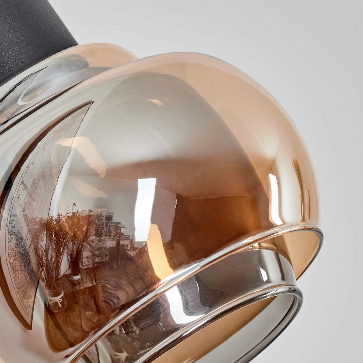 Nahaufnahme eines Lampenschirms aus Glas mit bräunlicher Tönung. Der Schirm hat eine reflektierende Oberfläche, der Hintergrund ist hellgrau.