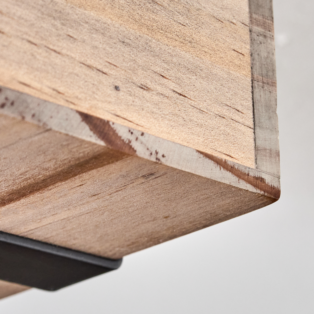 Nahaufnahme einer Holzeckablage. Das Holz ist hellbraun mit dunklen Linien. Eine schwarze Metallstütze ist unten sichtbar.