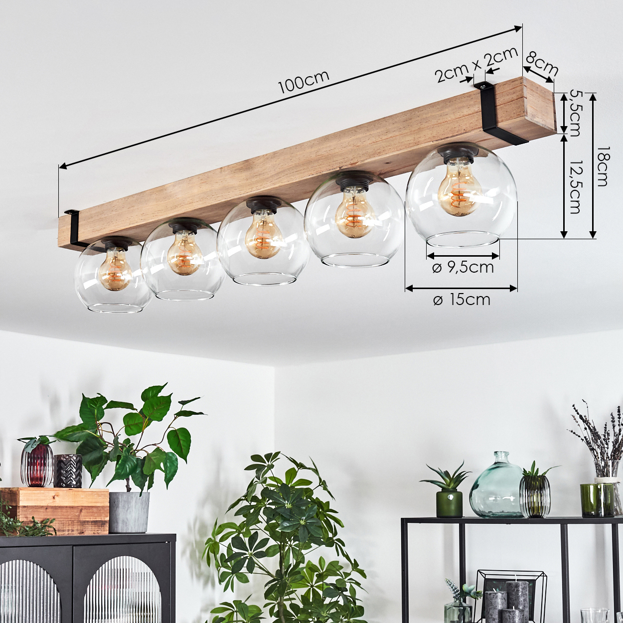 Ein Holzbalken mit fünf Glaskugel-Leuchten, die von der Decke hängen. Pflanzen und Dekoration im Vordergrund.
