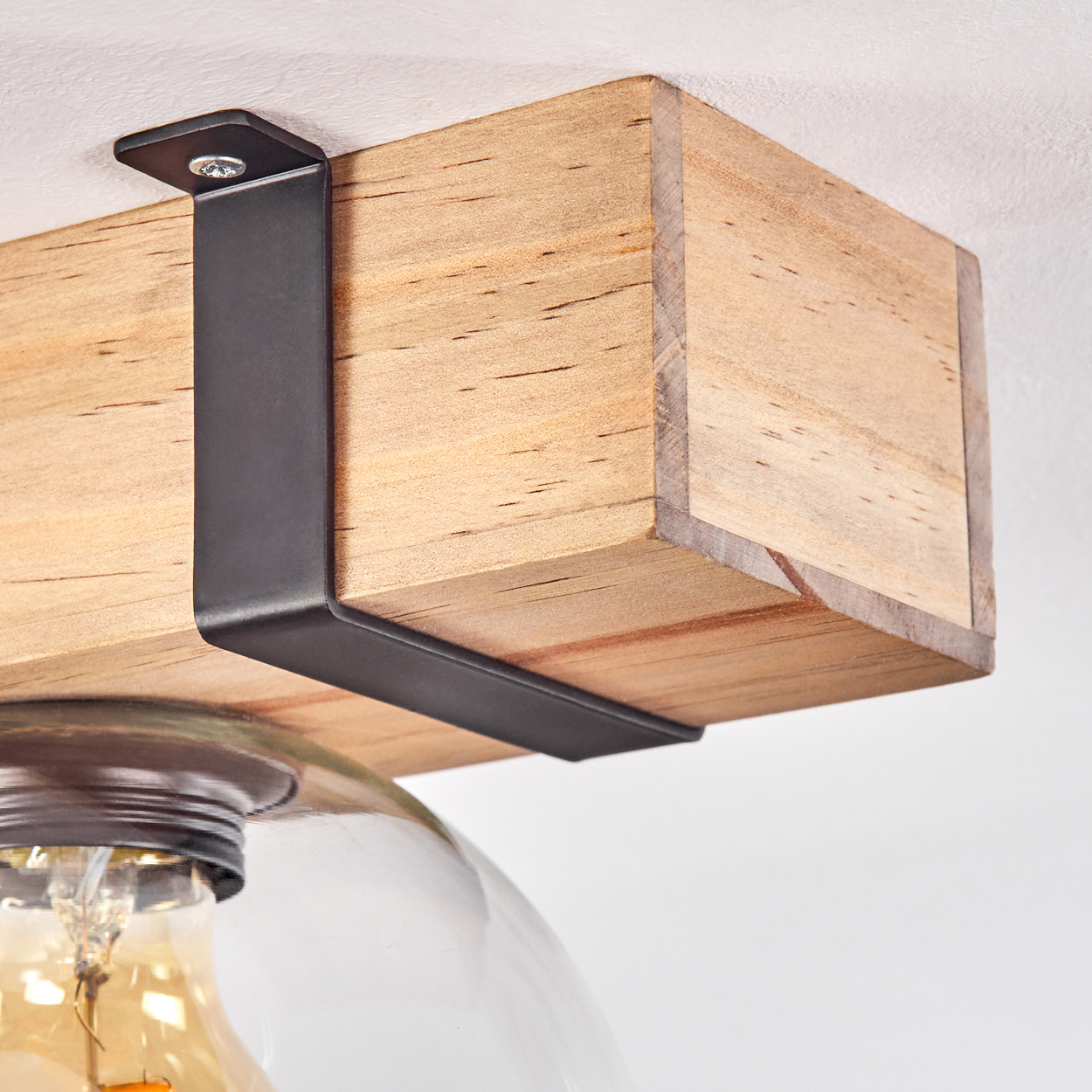 Ein Holzbalken mit schwarzen Metallhaltern hält eine Glaskugel-Leuchte. Die Glühbirne ist sichtbar. Der Hintergrund ist weiß.