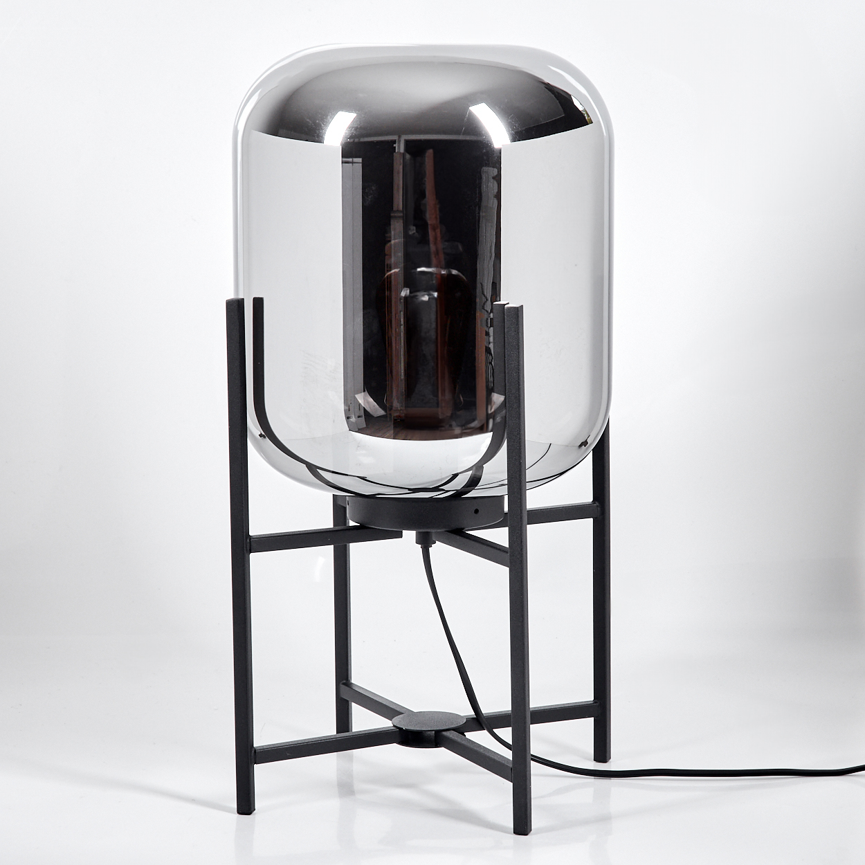 Eine moderne Lampe mit Glasschirm auf einem schwarzen Metallrahmen vor weißem Hintergrund.