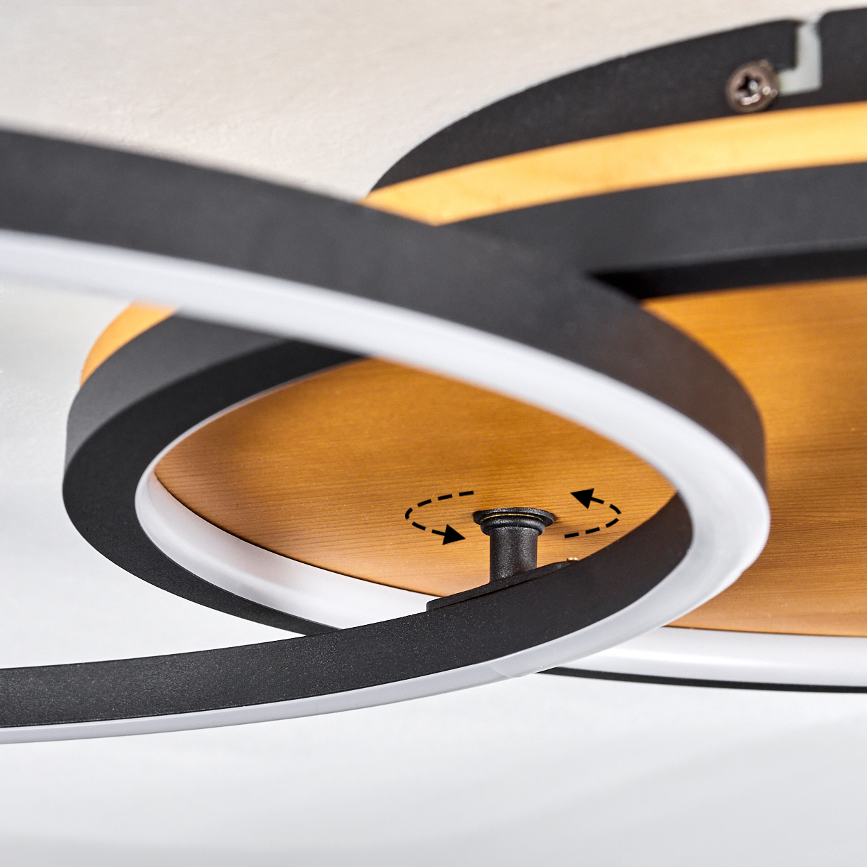 Nahaufnahme einer modernen Deckenlampe. Sie hat einen Holzsockel mit schwarzen und weißen Kreiselementen. Ein zentraler Knopf zeigt die Drehung an.