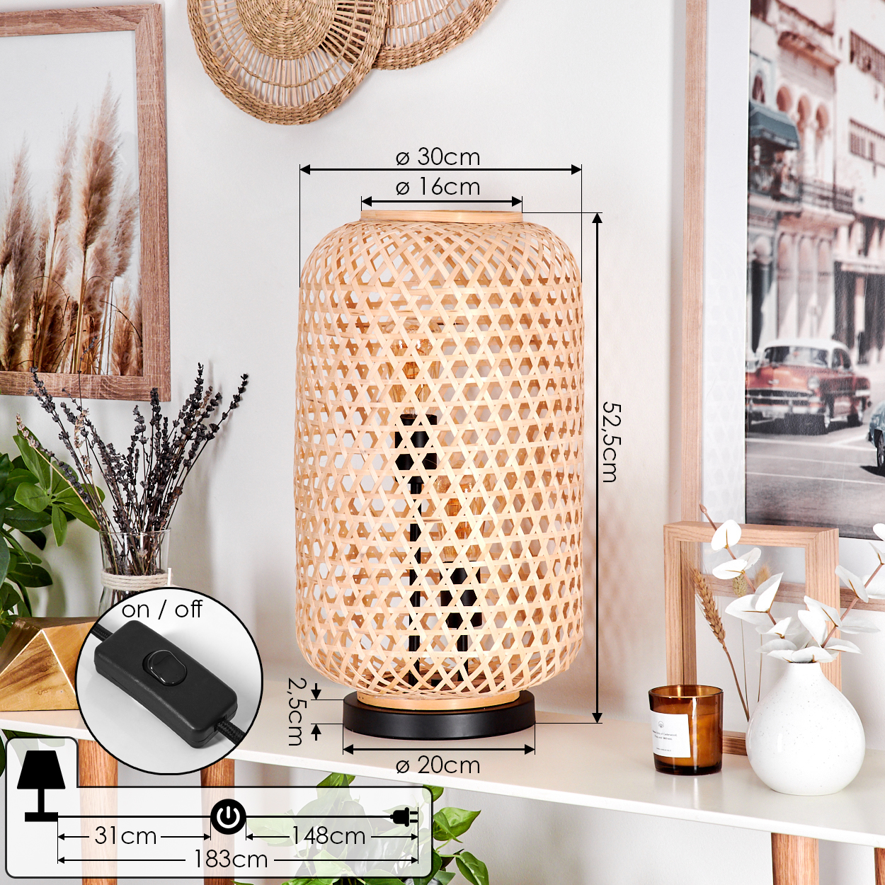 Eine Bambuslampe mit Maßen steht auf einem weißen Tisch. Weitere Dekorationen sind ein gerahmtes Bild und eine Kerze.