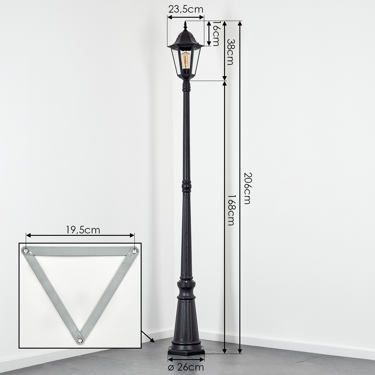 Eine schwarze Straßenlaterne mit Maßangaben. Eine dreieckige Metallbasis ist ebenfalls abgebildet. Der Hintergrund ist eine Ecke aus weißen Wänden und grauem Boden.