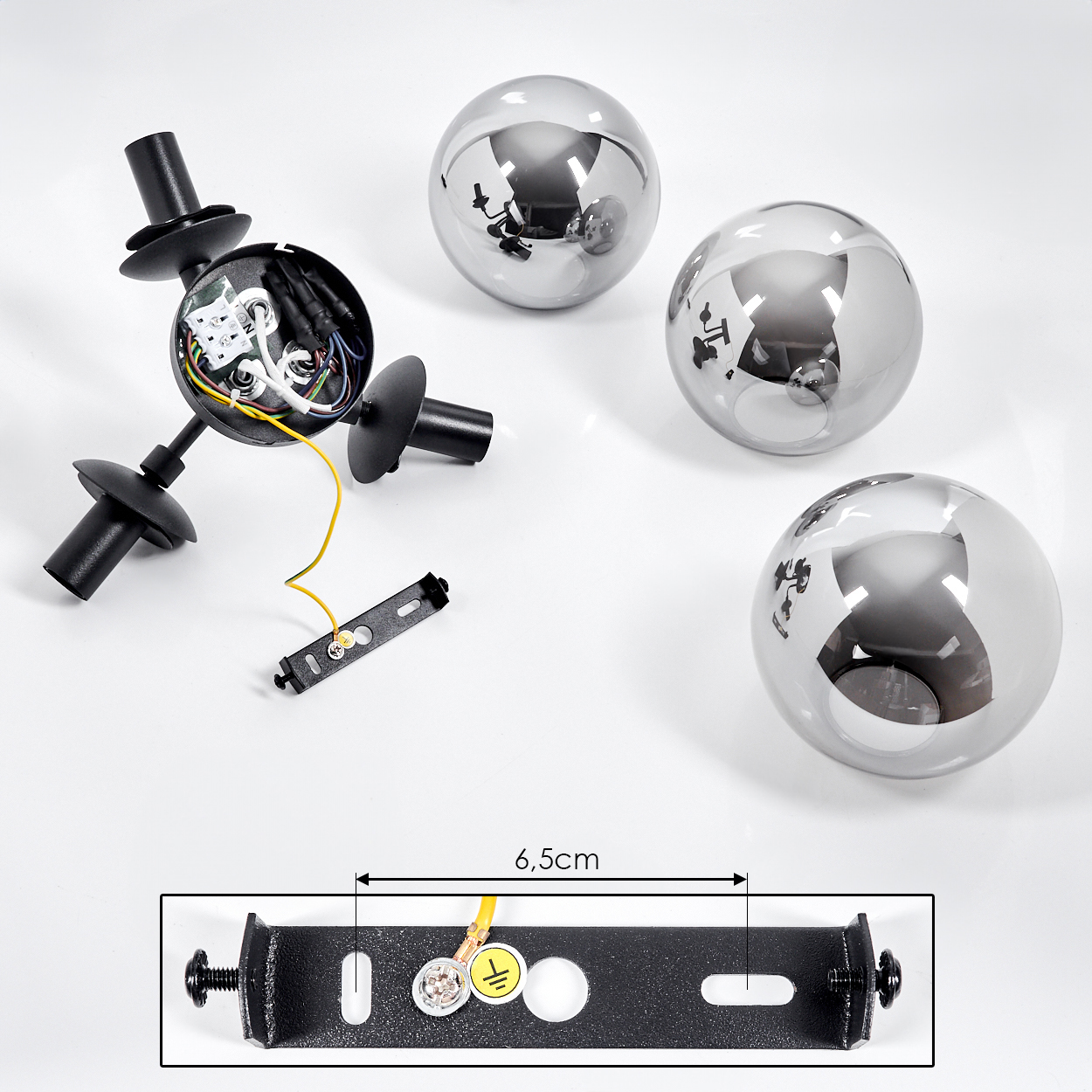 Bestandteile einer Lampe: schwarze Halterung, metallische Kugeln und eine schwarze Montagehalterung. Die Halterung hat ein gelbes Kabel.