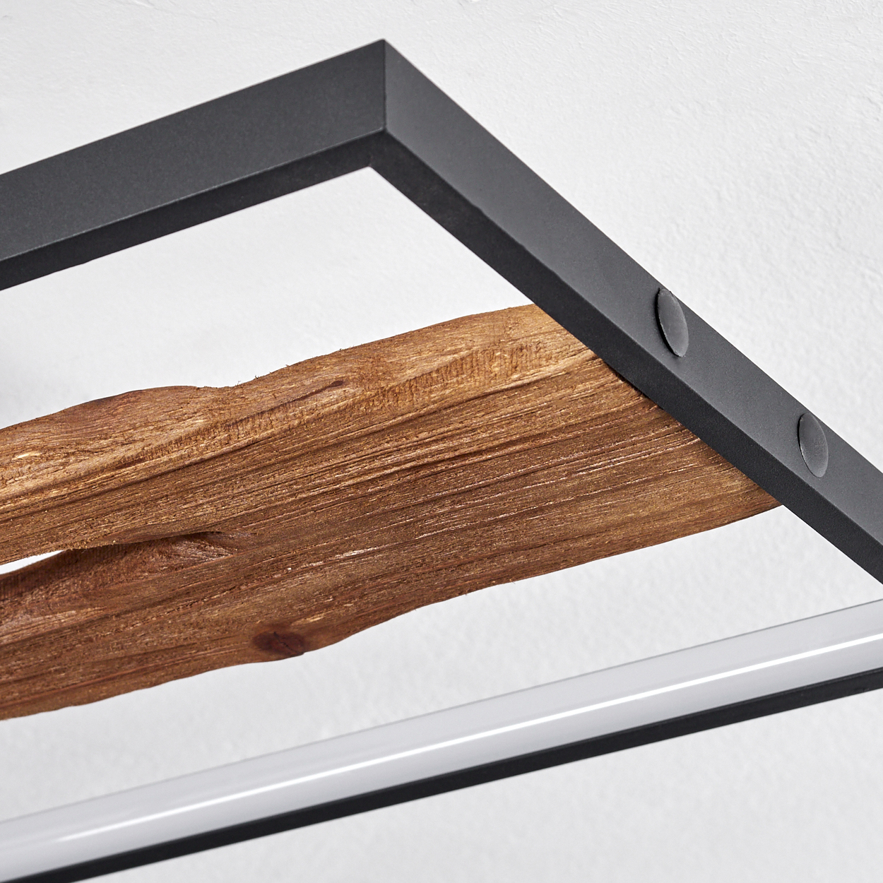 Nahaufnahme eines Holzregals, das von einem schwarzen Metallrahmen vor einer weißen Wand getragen wird. Das Holz hat eine raue Textur.