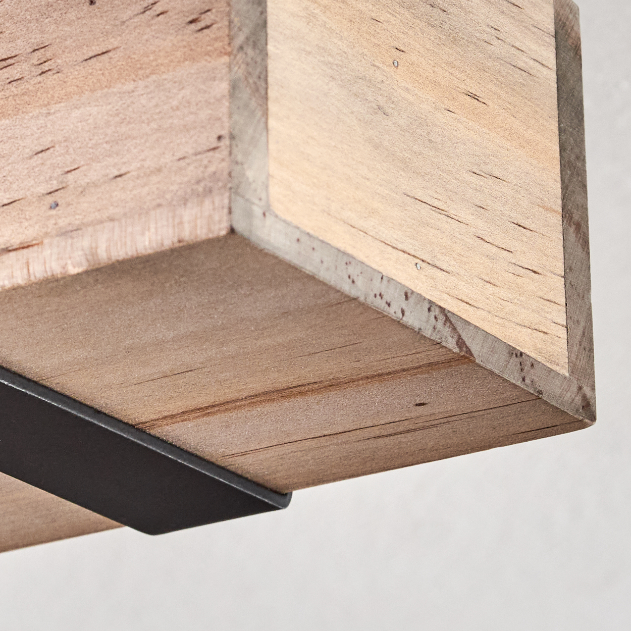 Nahaufnahme einer hölzernen Regal Ecke. Das Holz ist hellbraun mit sichtbarer Maserung. Eine schwarze Metallhalterung stützt das Regal.