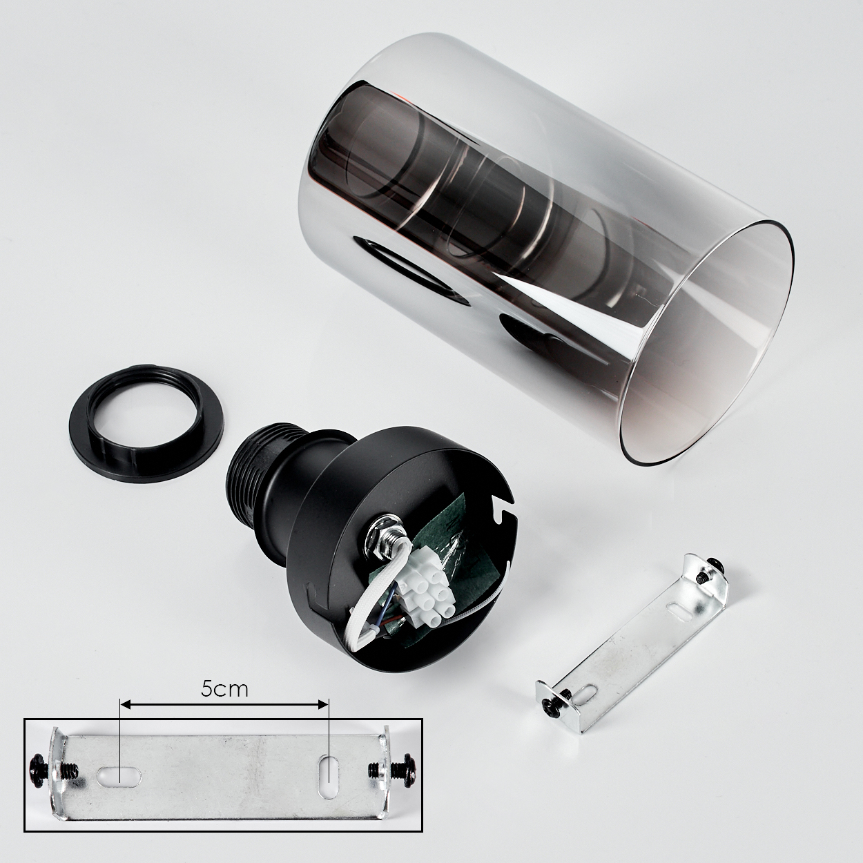 Zerlegte Lampenteile: Glaszylinder, schwarze Basis, Montagehalterung und Ring auf weißem Hintergrund. Eine 5-cm-Skala ist ebenfalls vorhanden.