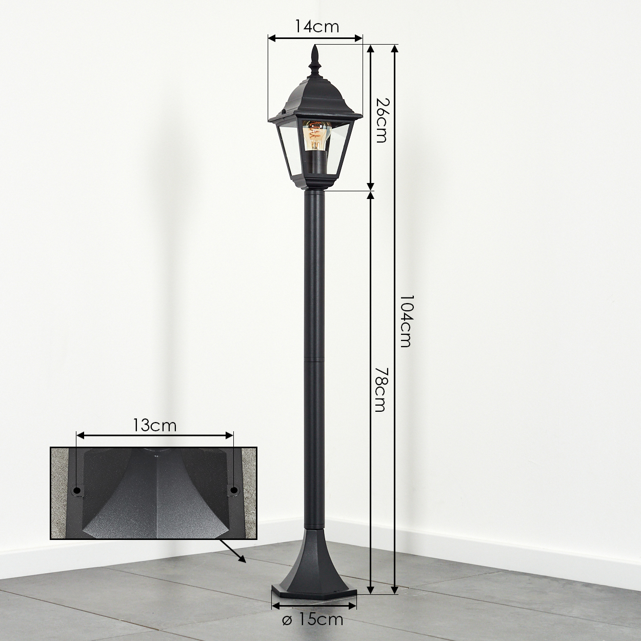 Eine schwarze Außenlampe mit einer Glühbirne im Inneren wird gezeigt. Abmessungen sind angegeben, einschließlich Höhen- und Breitenmessungen.