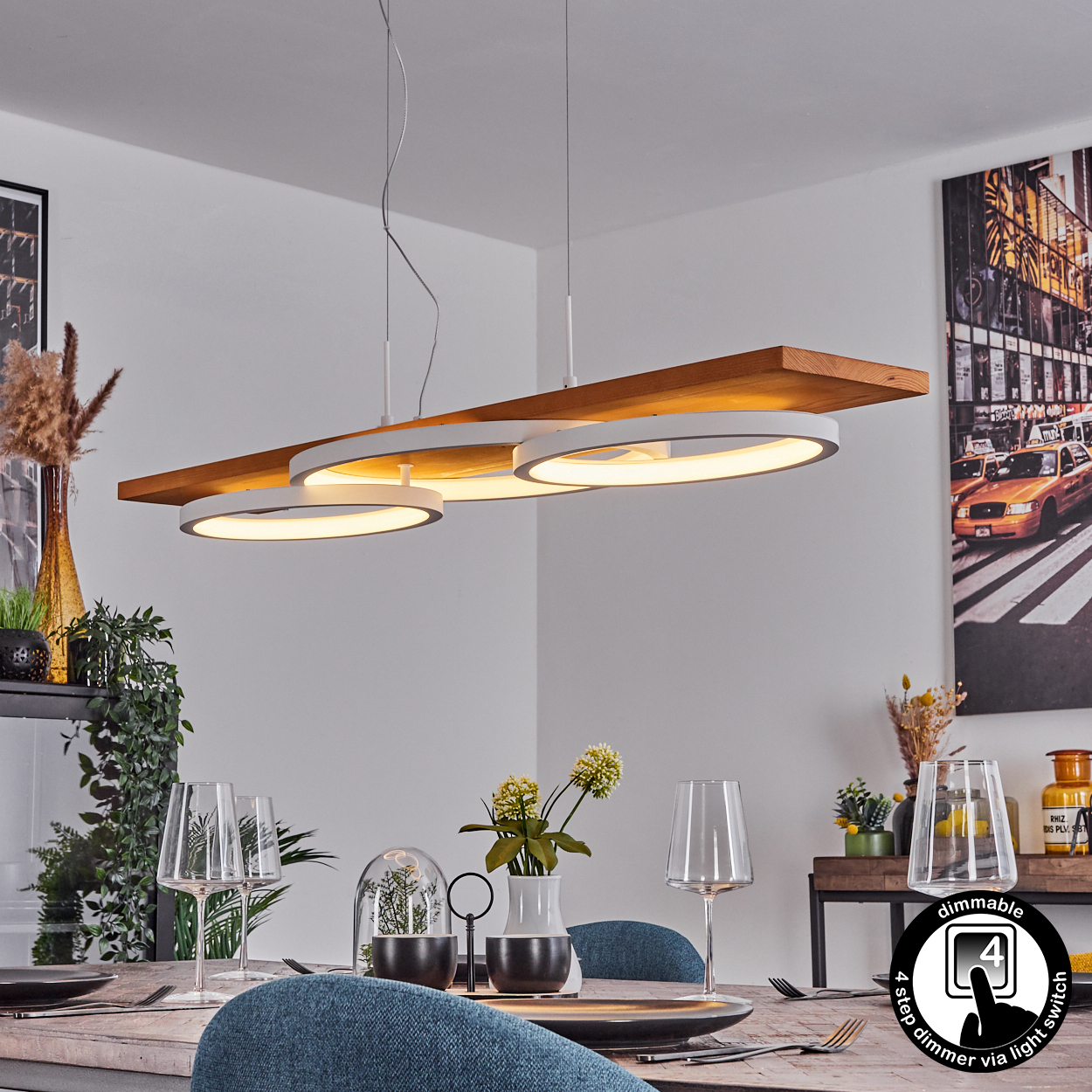 Ein Esszimmer mit einer Holz- und weißen Leuchte. Tisch mit Tellern, Gläsern und Blumen gedeckt. Ein New York City Bild an der Wand.