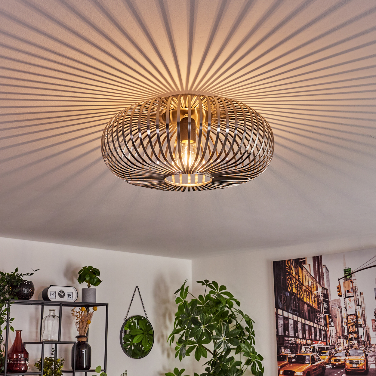 Eine moderne Deckenleuchte wirft radiale Schatten. Unten sind Pflanzen und ein Stadtbild zu sehen, was ein gemütliches Ambiente schafft.