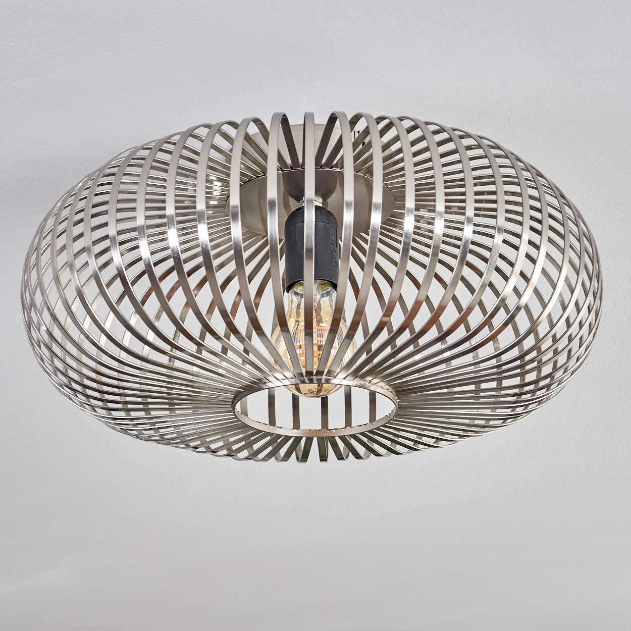 Eine moderne Deckenlampe mit metallischem, käfigartigem Design. Sie hat eine sichtbare Glühbirne und ist an einer weißen Decke befestigt.