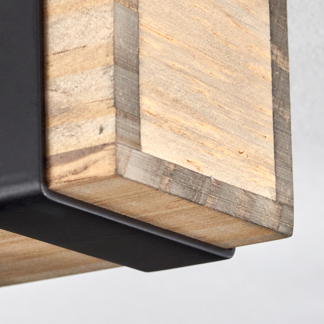 Nahaufnahme eines Holzbalkens mit schwarzen Metallstützen. Das Holz ist hellbraun mit dunklerem Besatz. Weißer Hintergrund.
