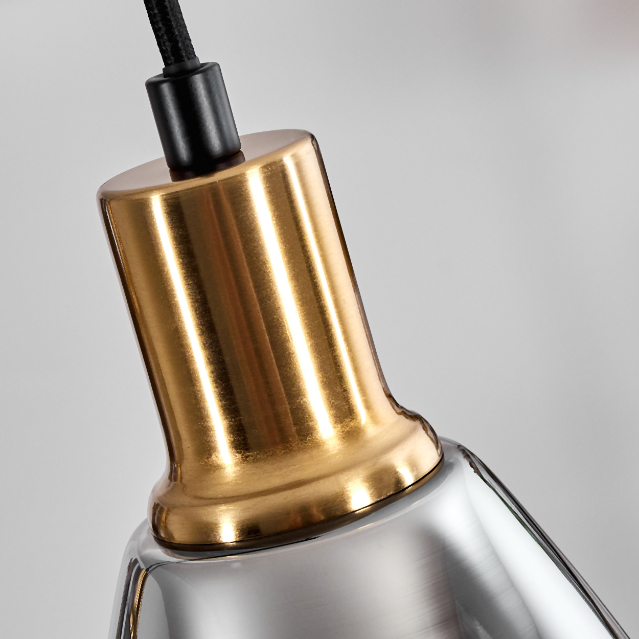 Nahaufnahme einer Lampenfassung. Sie hat eine goldfarbene Oberseite und eine silberfarbene Unterseite. Ein schwarzes Kabel ist befestigt.