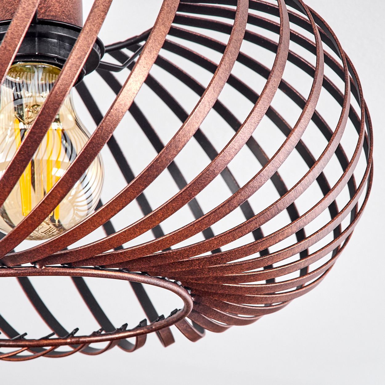 Nahaufnahme einer bronzefarbenen, spiralförmigen Leuchte mit sichtbarer Glühbirne vor weißem Hintergrund.