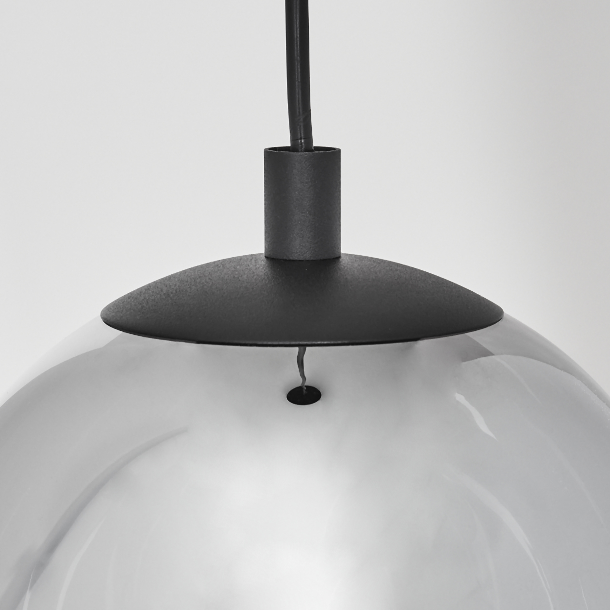 Nahaufnahme einer modernen Lampe. Die Lampe hat einen schwarzen Metallsockel und einen reflektierenden, halbtransparenten Glasschirm.