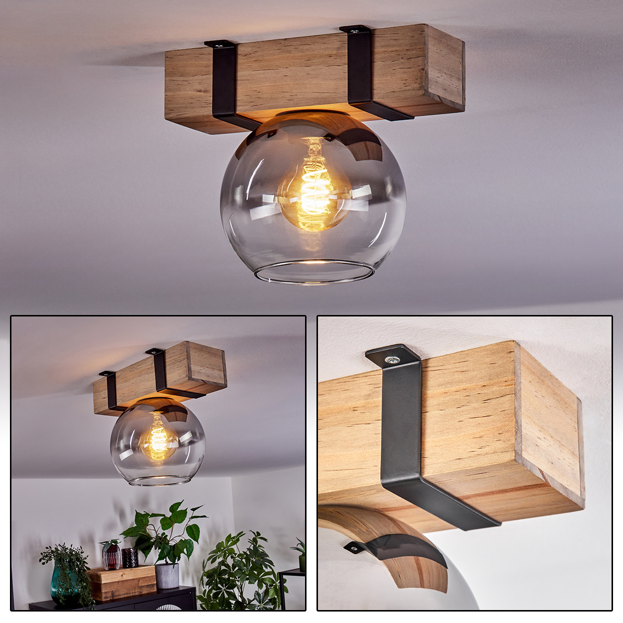 Eine Deckenlampe mit Holzbalken und Glaskugel. Die Glühbirne leuchtet. Schwarze Halterungen halten den Balken. Pflanzen im Hintergrund.